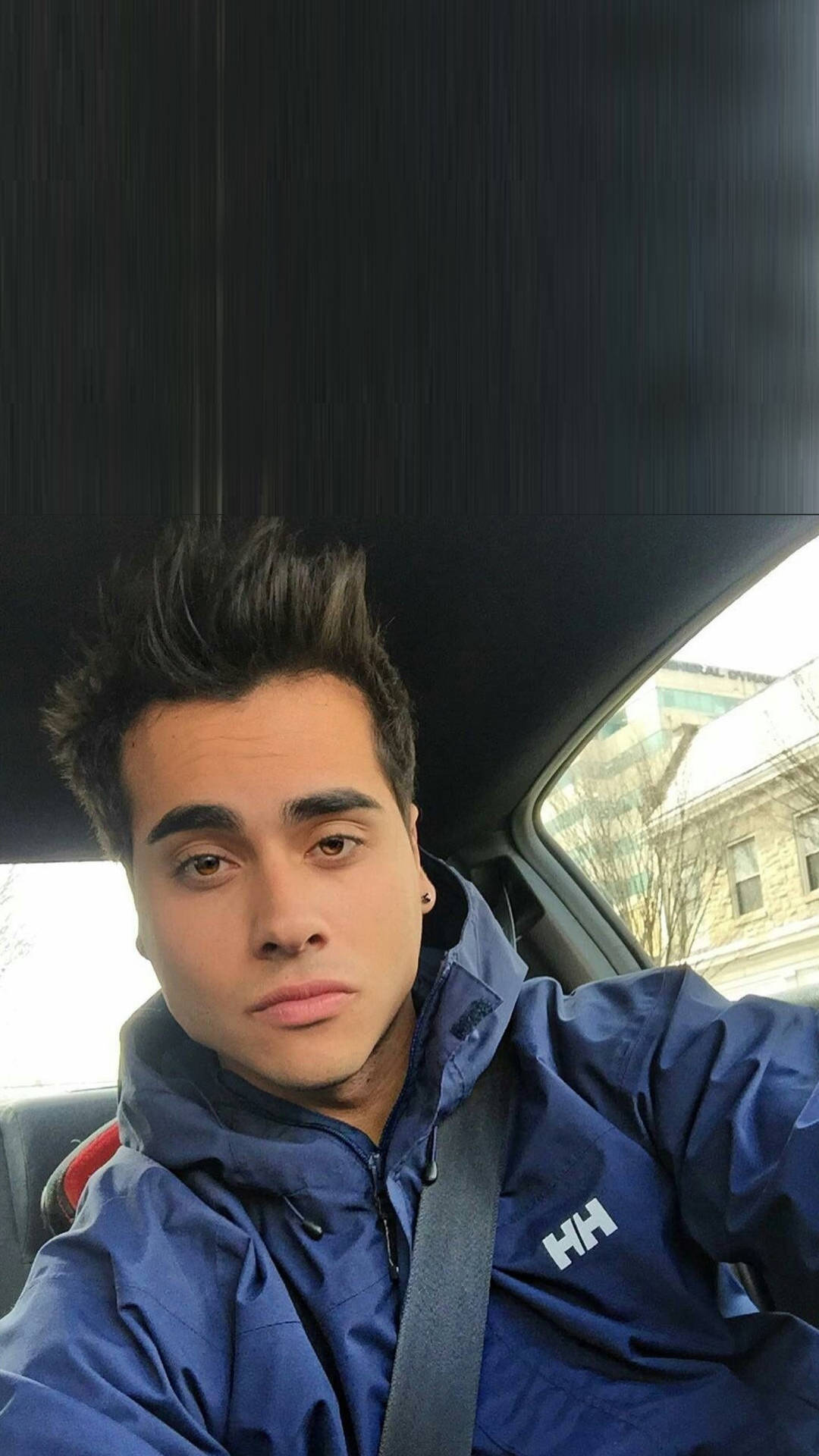 身穿藍色外套的年輕男子繫著安全帶坐在車內