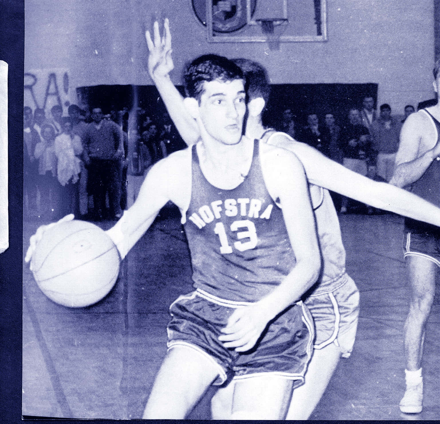 Dolph Schayes NBA傳奇 壁紙 — 一張復古黑白照片捕捉到霍夫斯特拉大學籃球運動員在體育館中運球並被防守的動作。