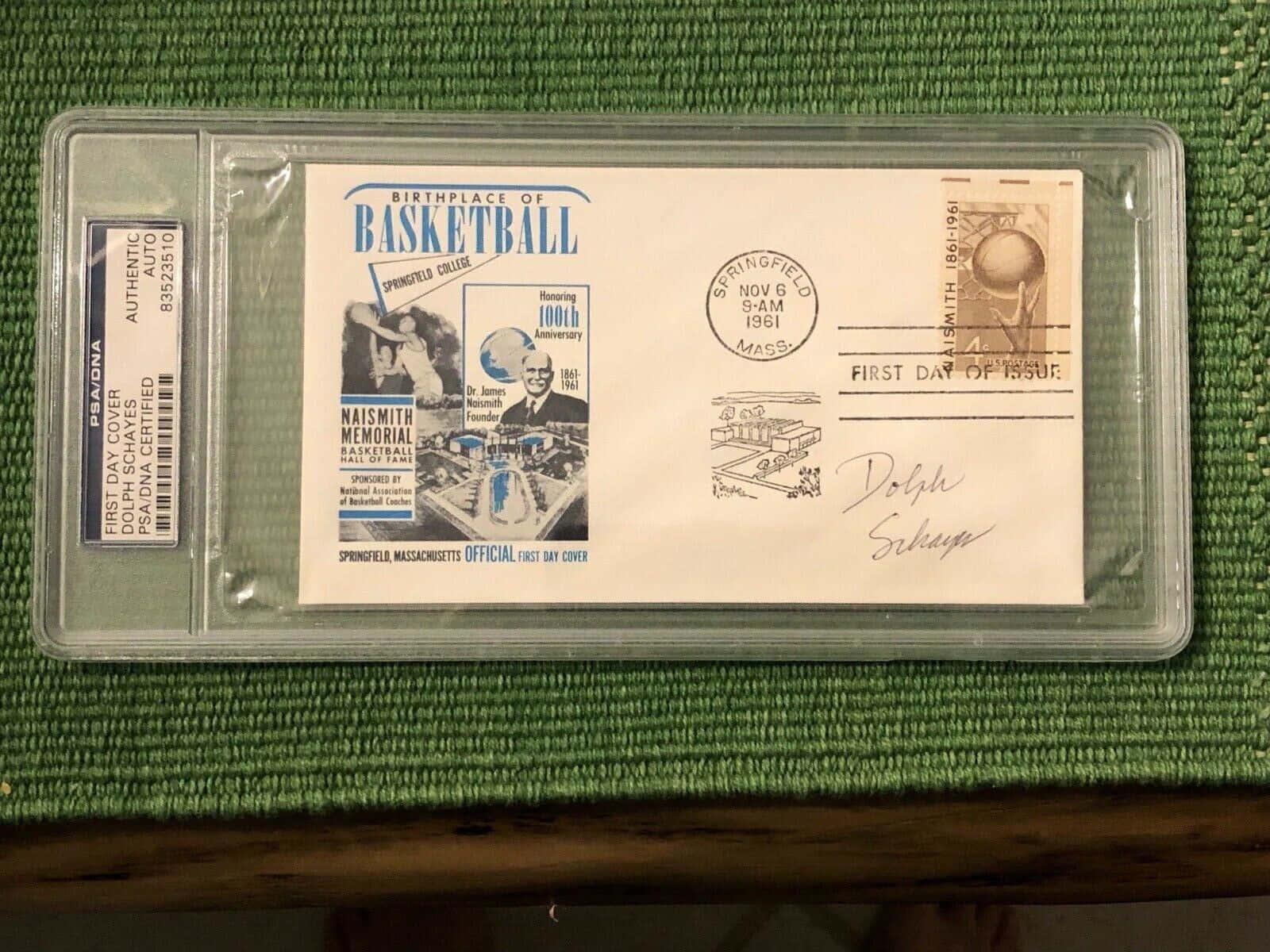 簽名1961年籃球首日封，PSA/DNA封裝盒，綠色布料上。