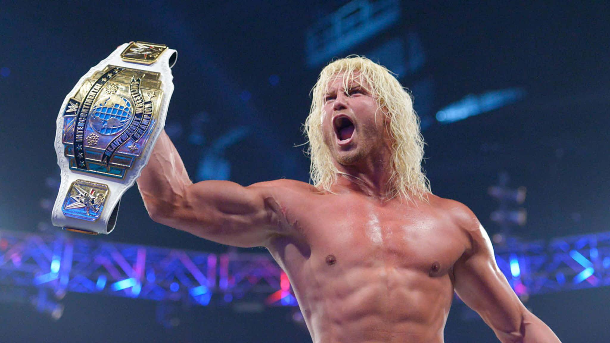 Dolph Ziggler 擁有 Money in the Bank 箱 壁紙 — 一位肌肉發達的金髮摔角手在場館燈光下高舉閃閃發光的冠軍腰帶，發出勝利的咆哮。