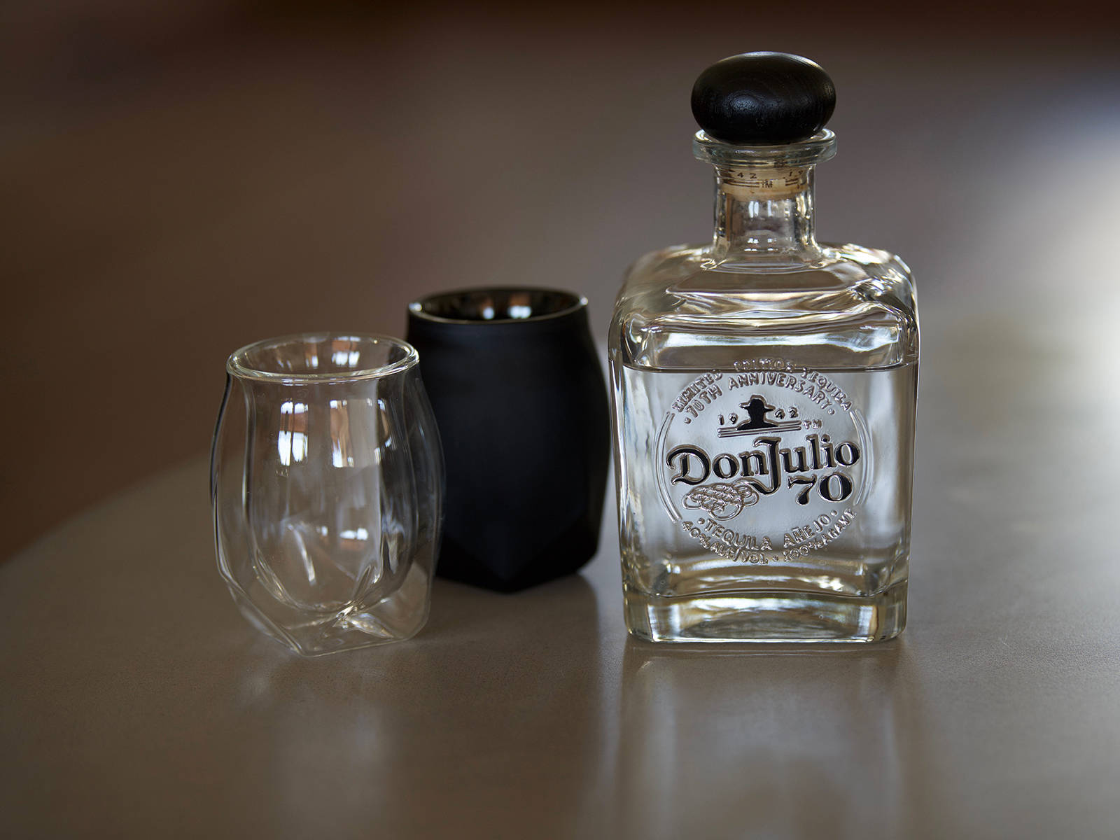 Don Julio 70龍舌蘭酒樽連同兩個酒杯喺木枱上。