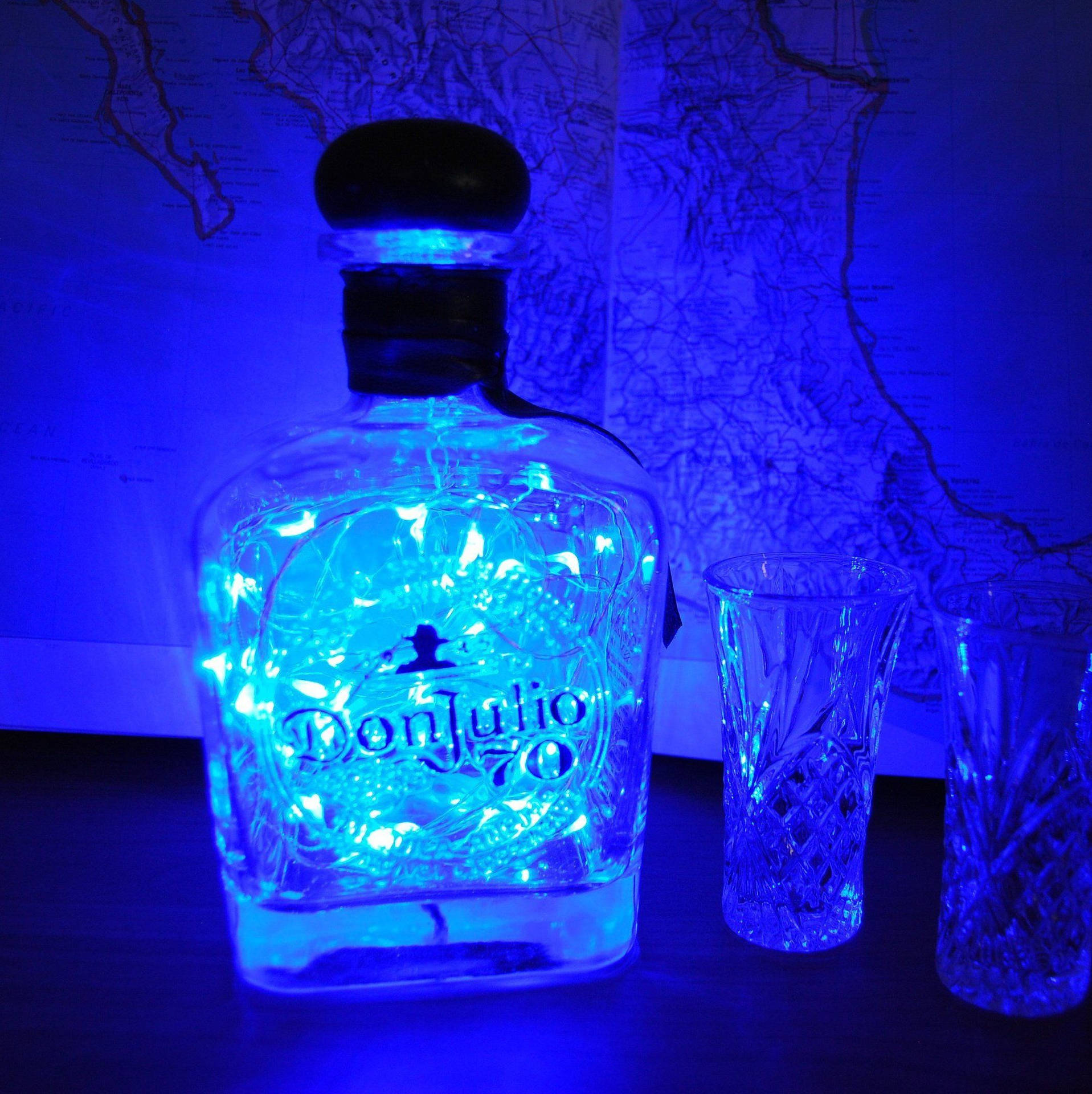 在地圖背景上，藍色發光龍舌蘭酒瓶與水晶杯。