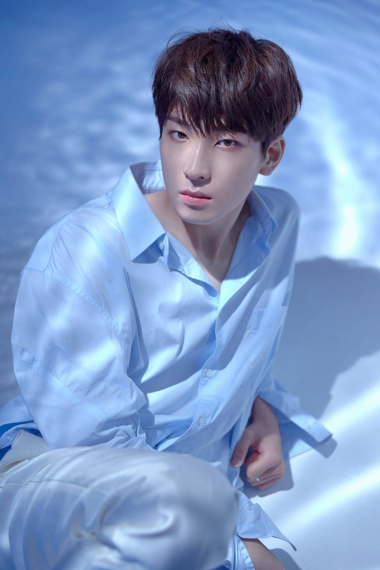 全圓佑《Don't Wanna Cry》拍攝 壁紙 — 一位身穿淺藍色襯衫的年輕男子坐在反射表面上，處於帶有柔和陰影的清涼藍色燈光下。