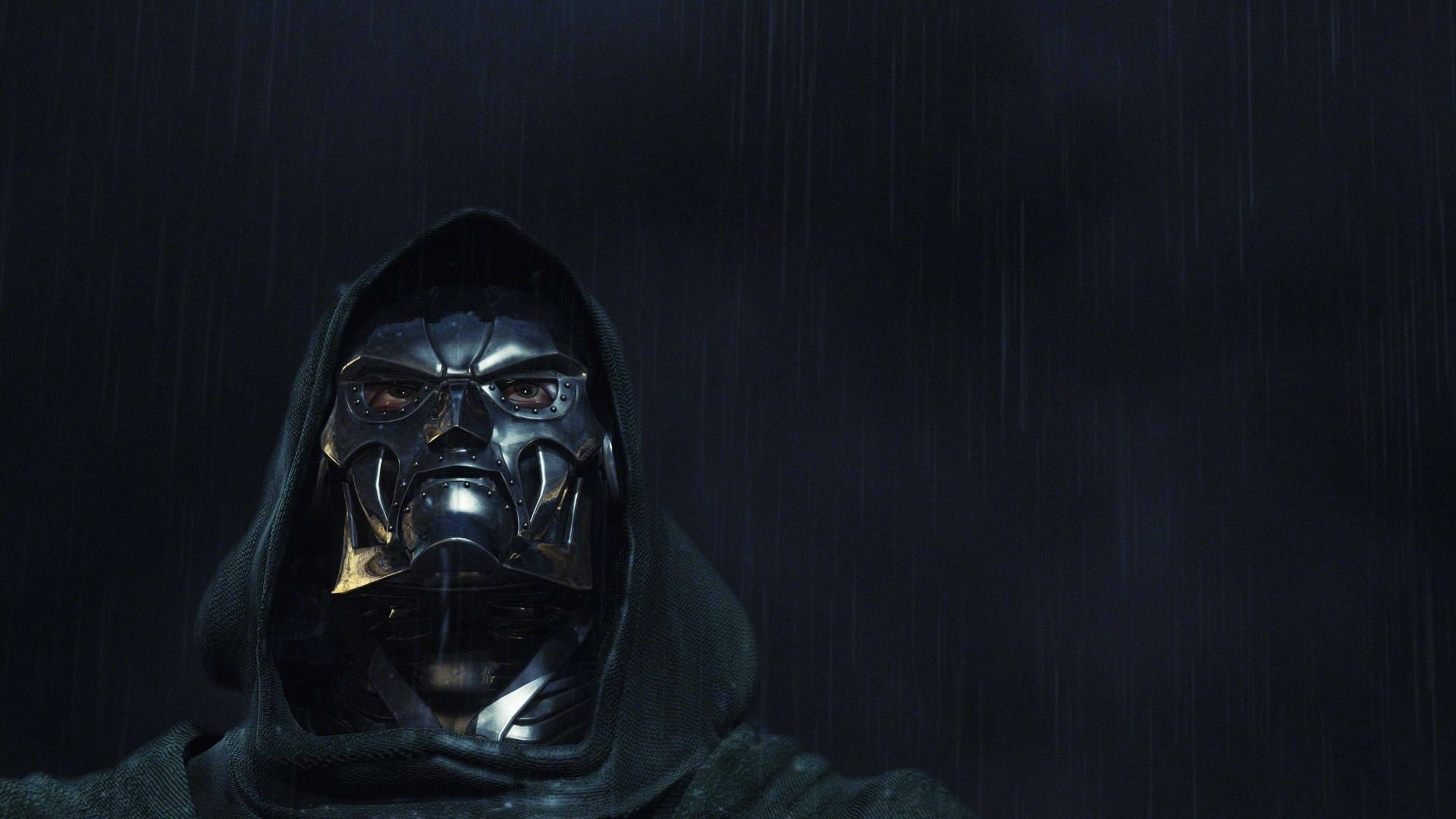 暗黑 Doom 博士 壁紙 — 一個戴著深色兜帽的威脅性蒙面人物站在傾盆大雨中，天空陰沉。