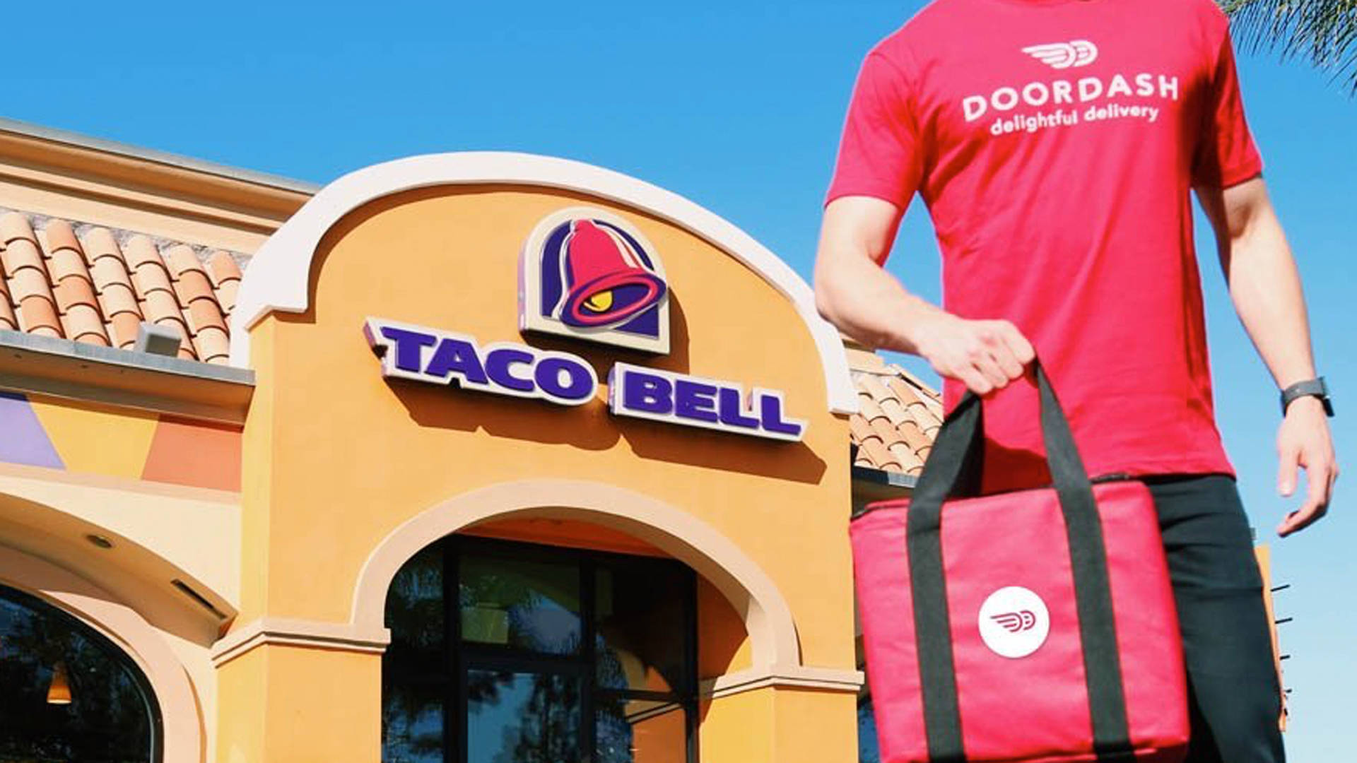 塔可鐘與DoorDash外送合作海報 壁紙 — 一名Doordash送貨員站在Taco Bell餐廳外，在晴朗的藍天下拿著一個紅色保溫袋。