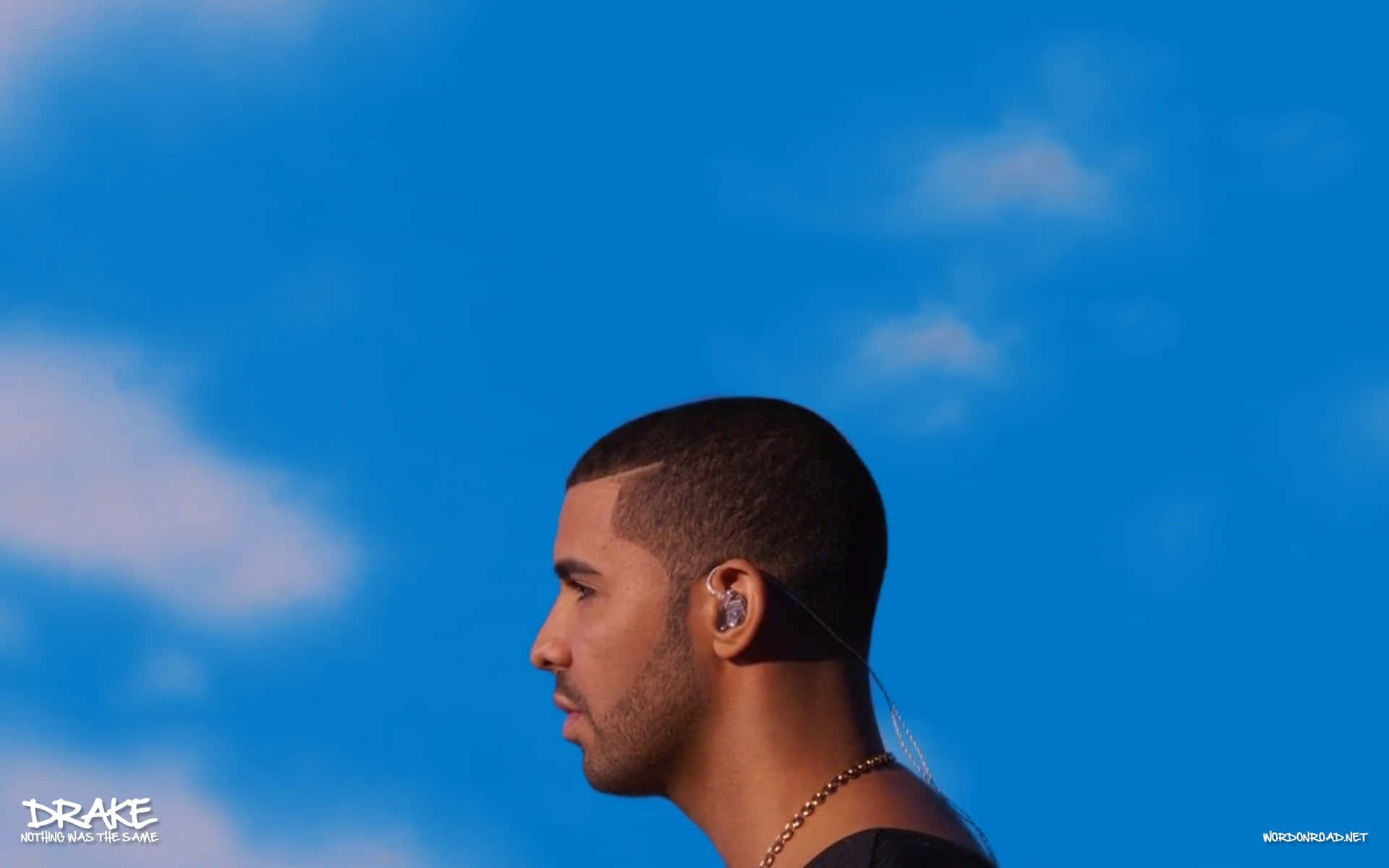 Drake 側面輪廓，戴住耳機同金鏈，背景係藍天白雲。