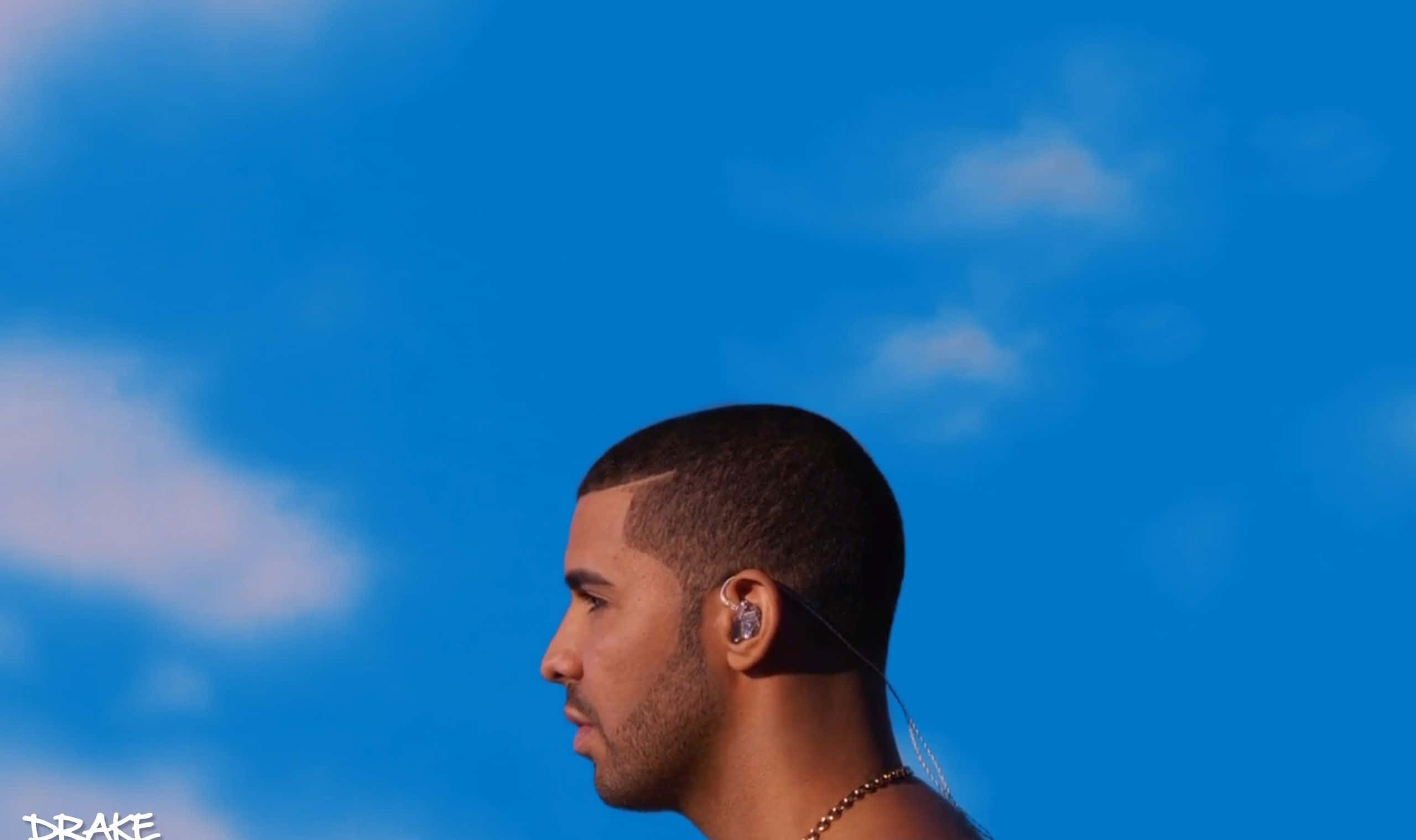 Drake 桌布 壁紙 — Drake 側面照，背景係鮮豔嘅藍天同柔和嘅白雲，戴住耳機同金鏈。