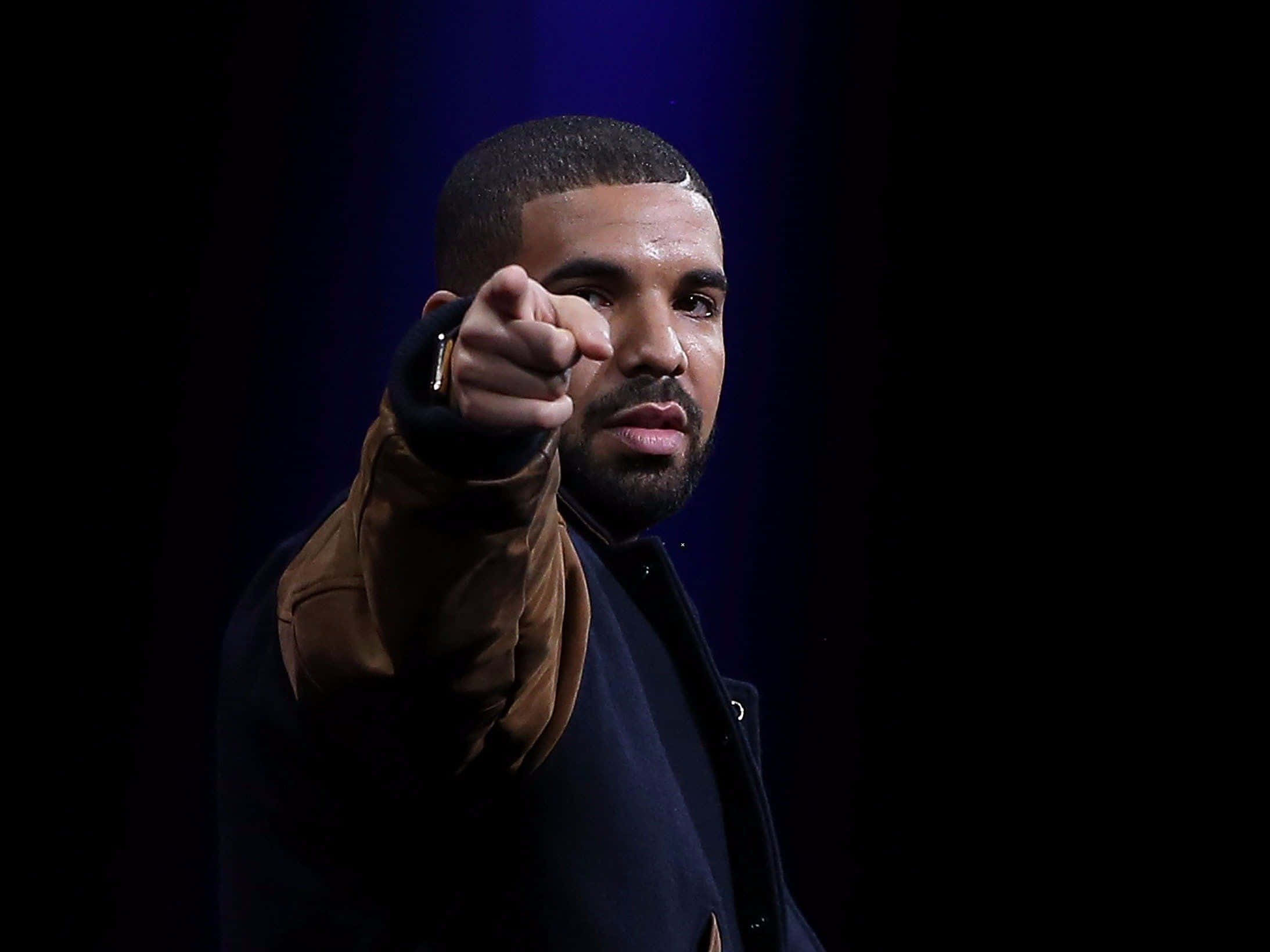 Drake 桌布 壁紙 — Drake 在黑暗背景下，於戲劇性的藍色舞台燈光下直接指向觀眾。