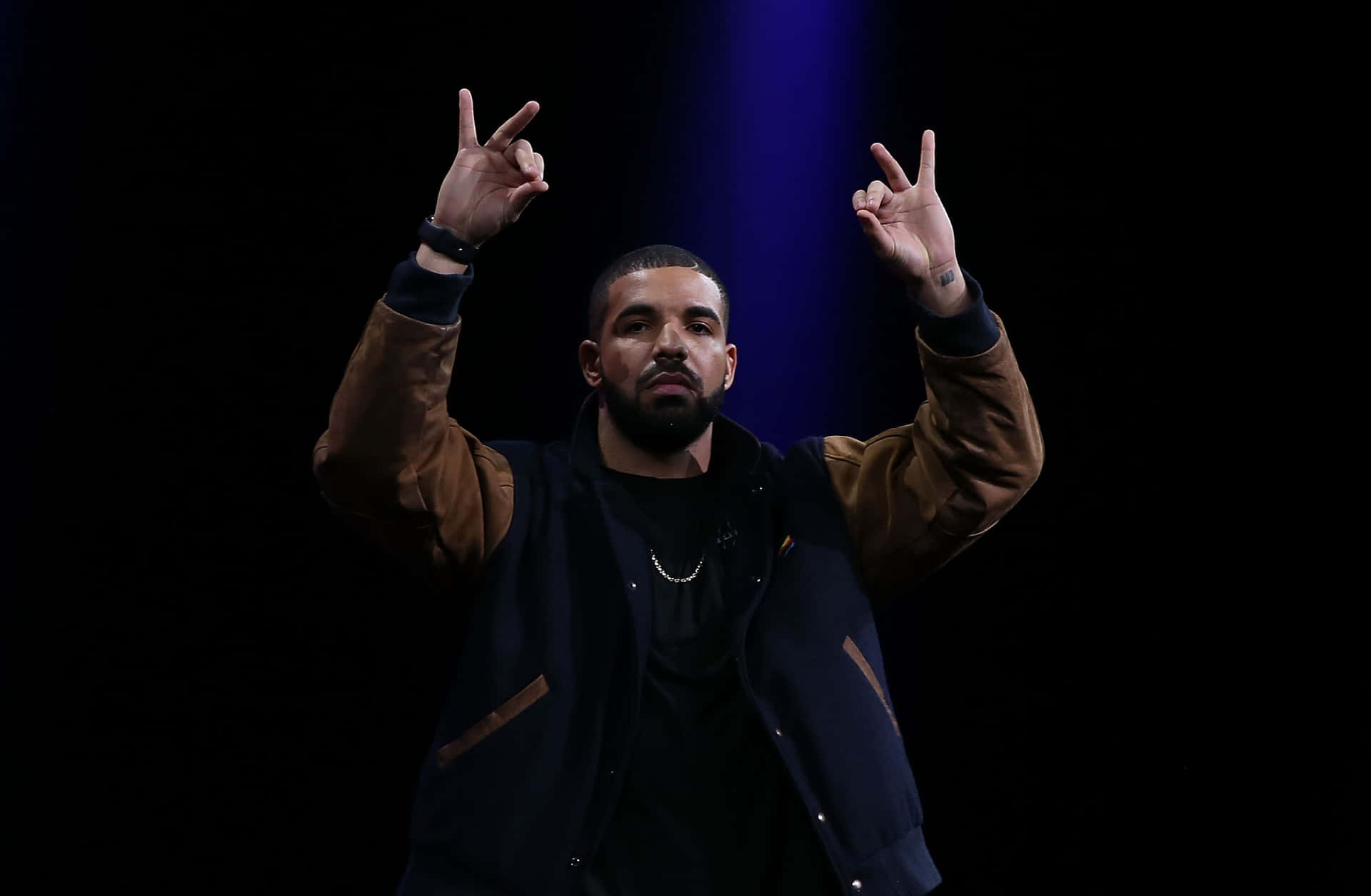 Drake 在舞台上舉起雙手做手勢表演。