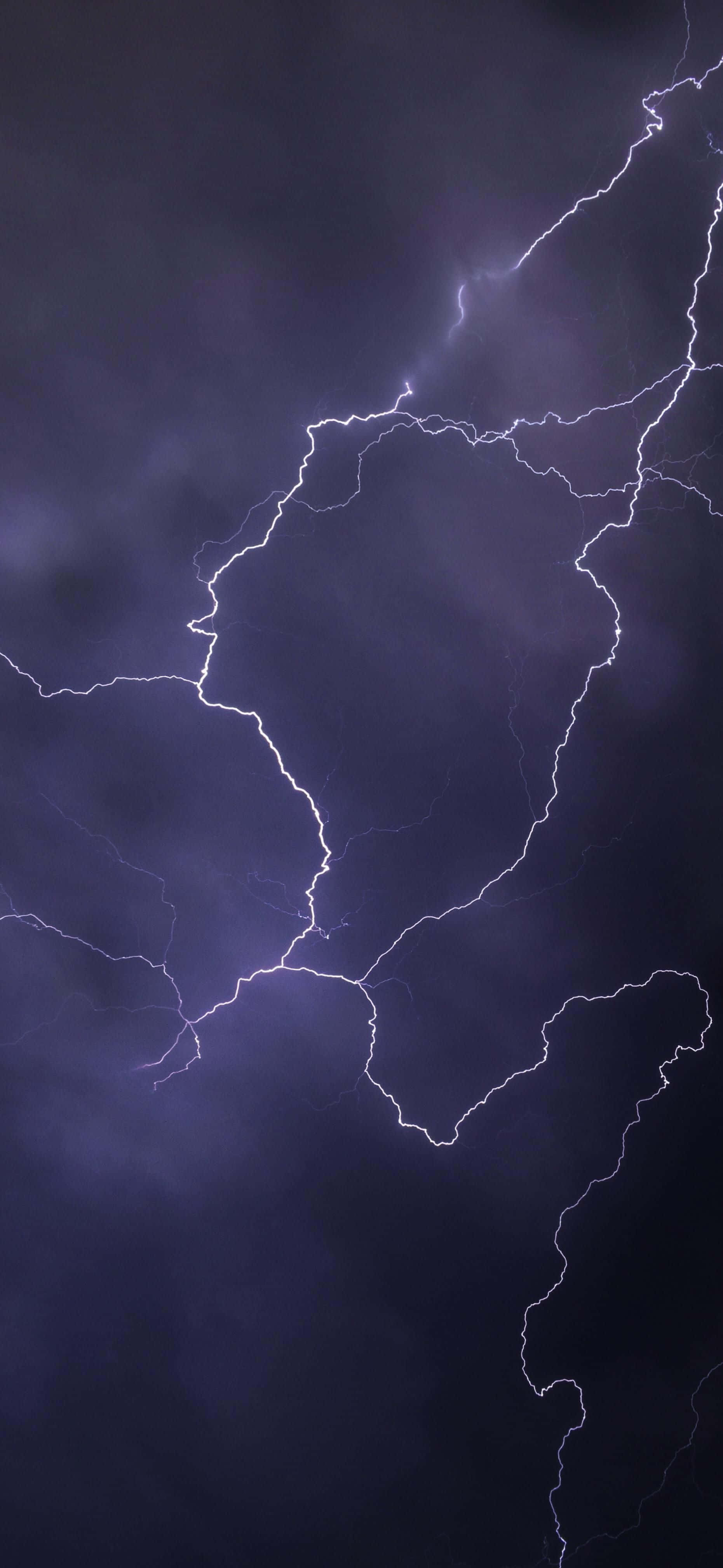 Lightning iPhone 桌布 壁紙 — 一道戲劇性的閃電在黑暗暴風雨的天空中分叉，呈現鮮明的電光紫和白色。