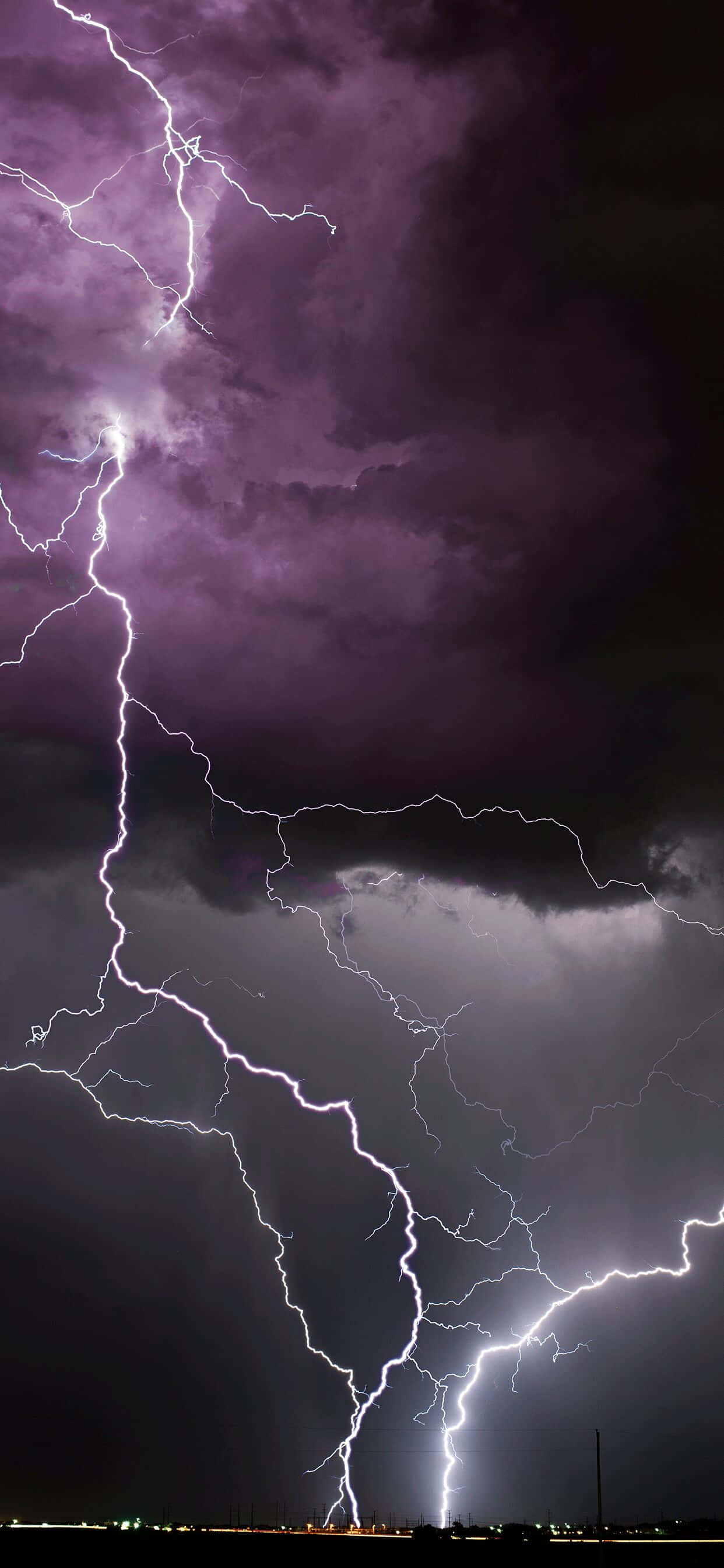 Lightning iPhone 桌布 壁紙 — 戲劇性的夜空被多道鮮明的閃電劃破，映襯著深紫色的暴風雲。
