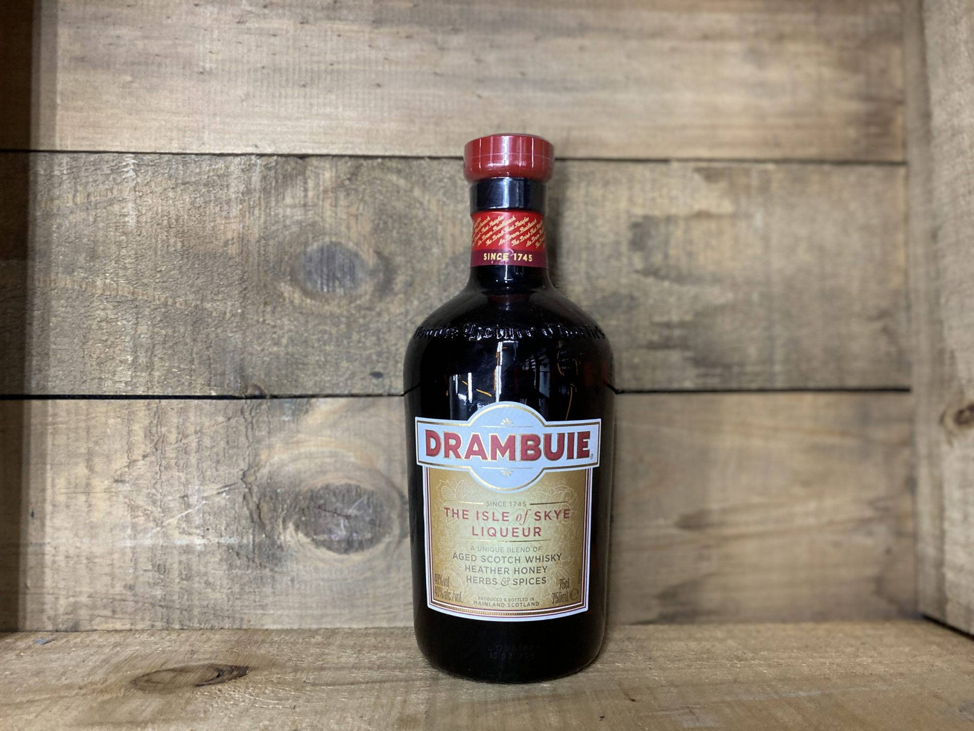 Drambuie 利口酒瓶在木質表面上，背景為木牆