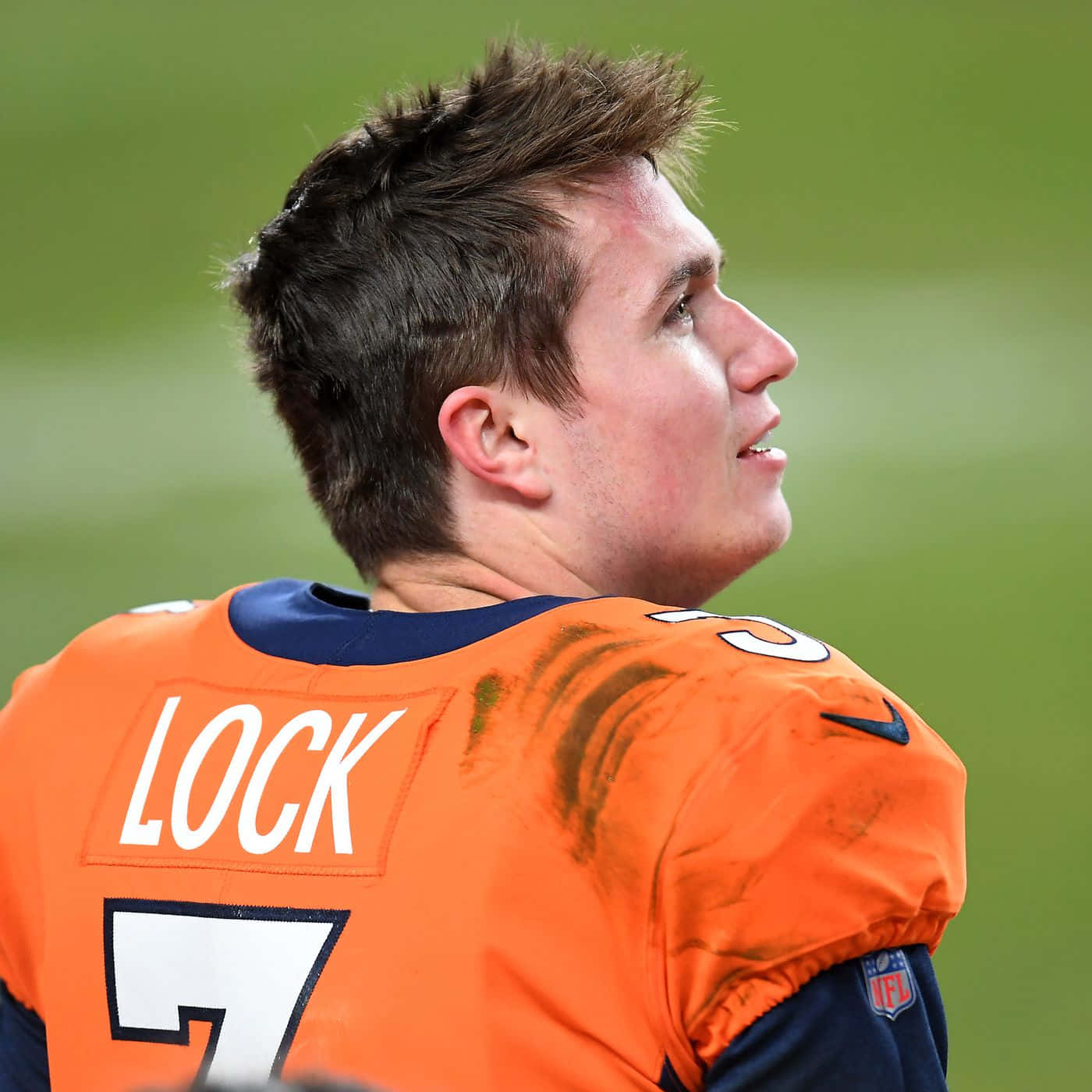 Drew Lock丹佛野馬隊四分衛 壁紙 — 近距離拍攝一名身穿橙色球衣、上面有「LOCK」和號碼7的足球員，在綠色球場上望向一旁。