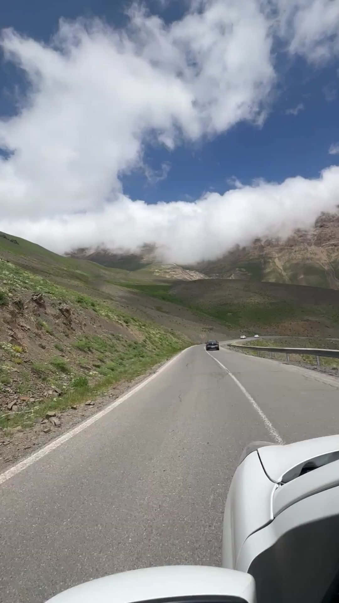 白色汽車在蜿蜒的山路上，有雲和藍天