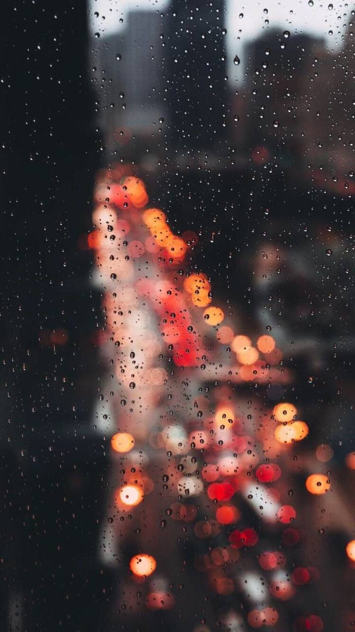窗戶上的雨滴，夜晚模糊的城市燈光溫暖地發光。