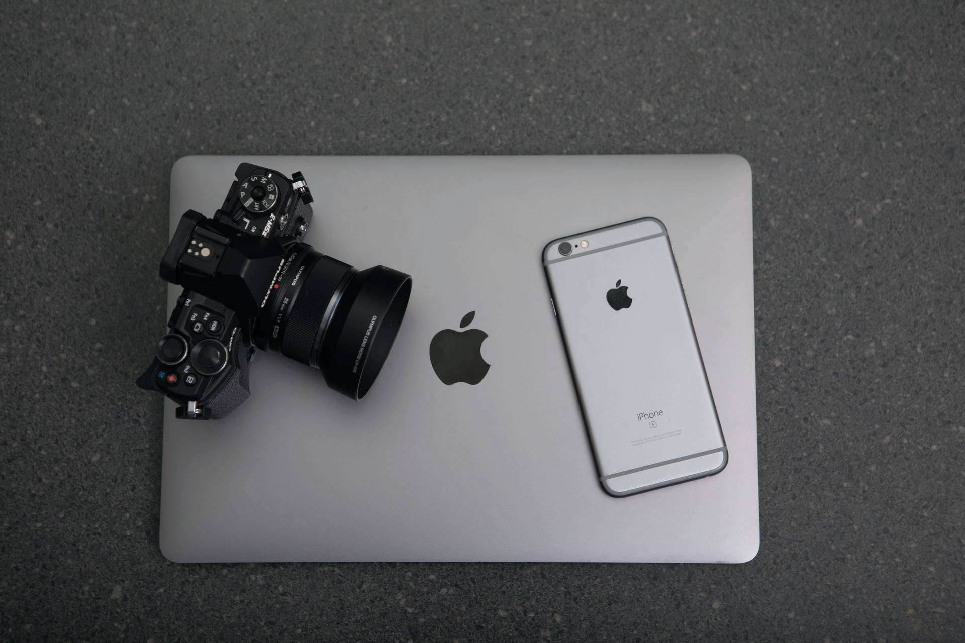閉合MacBook筆記本電腦上的黑色單反相機和銀色iPhone。