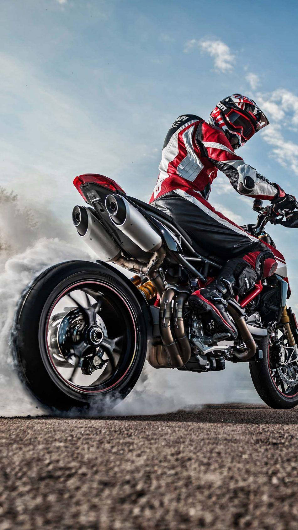 Ducati Hypermotard 4K摩托車 壁紙 — 一名身穿紅白裝備的電單車手在運動型電單車上傾斜入彎，在明亮的藍天下踢起碎石。
