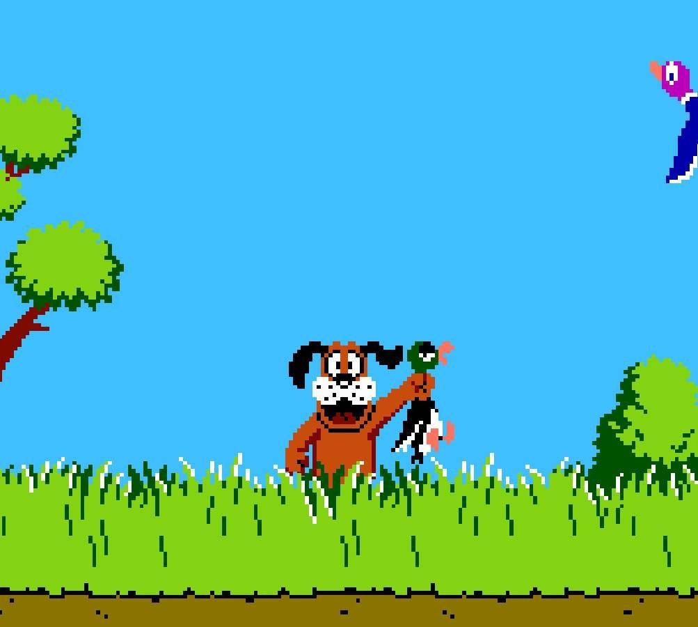 Duck Hunt 近景遊戲畫面 壁紙 — 一隻像素化的狗喺藍天白雲下嘅草地上捉住一隻鴨，周圍有樹同埋一隻飛緊嘅雀。