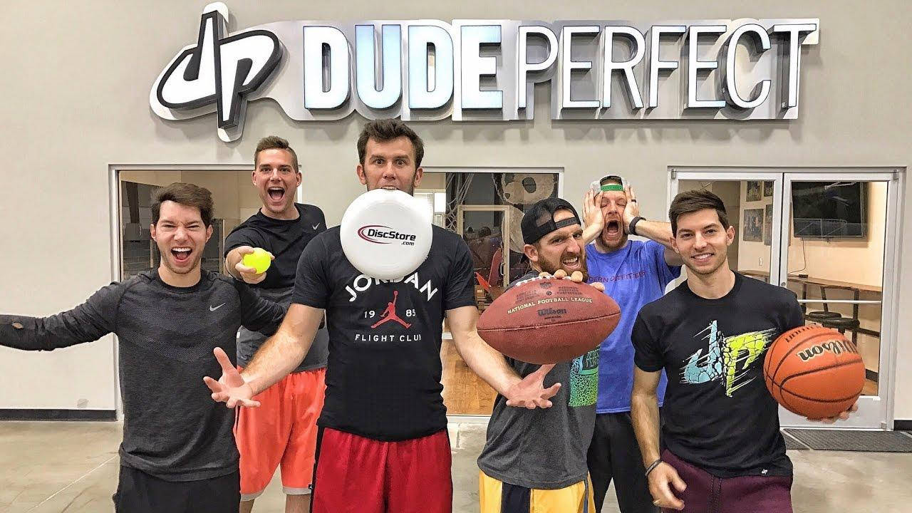 Dude Perfect 健身房內 壁紙 — 五名男子在攝影棚內於Dude Perfect標誌下充滿活力地擺出姿勢，手持運動裝備。