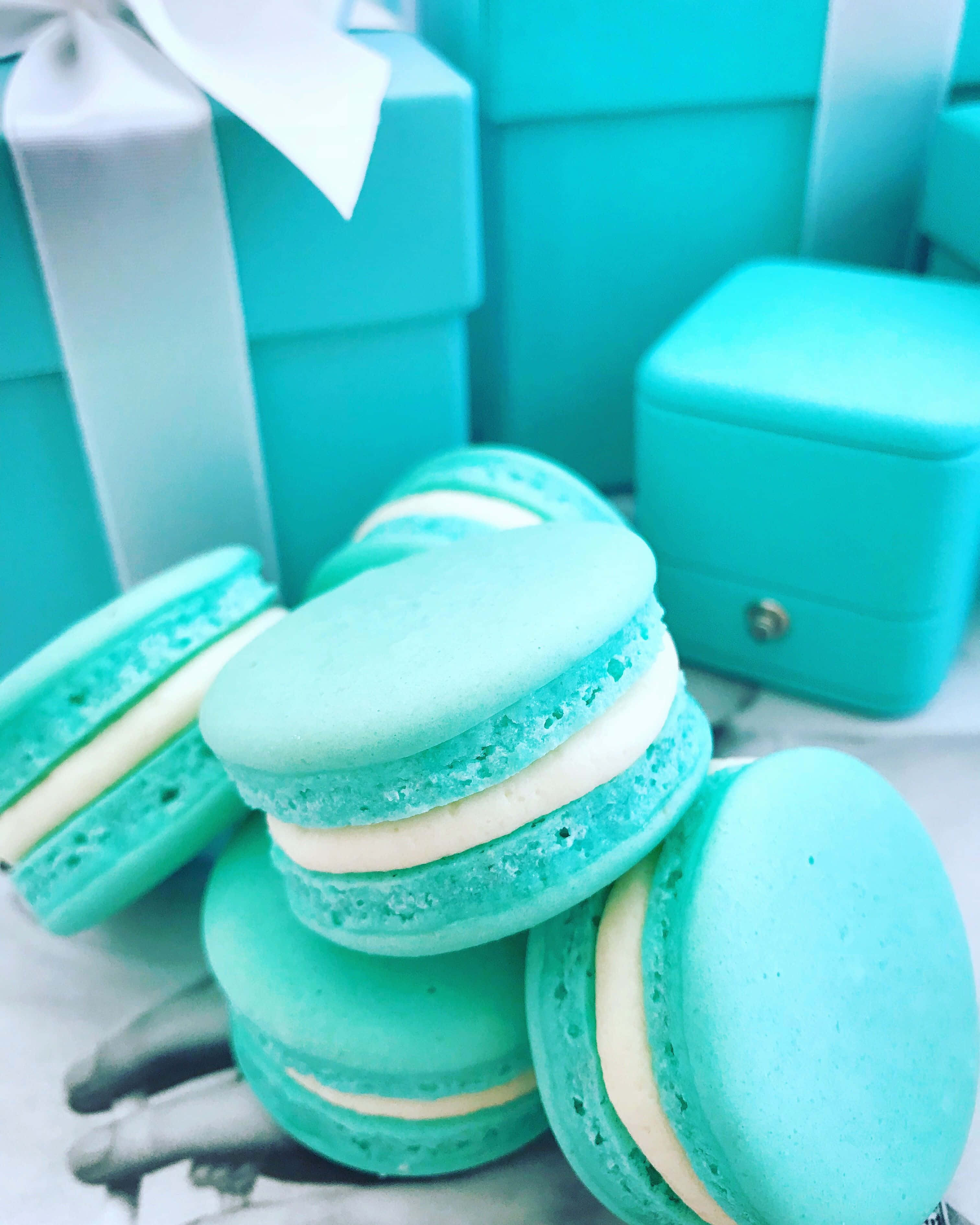 Turquoise Blue 桌布 壁紙 — 堆疊的綠松石馬卡龍配白色奶油，旁邊是配套的禮品盒，放在大理石表面上。