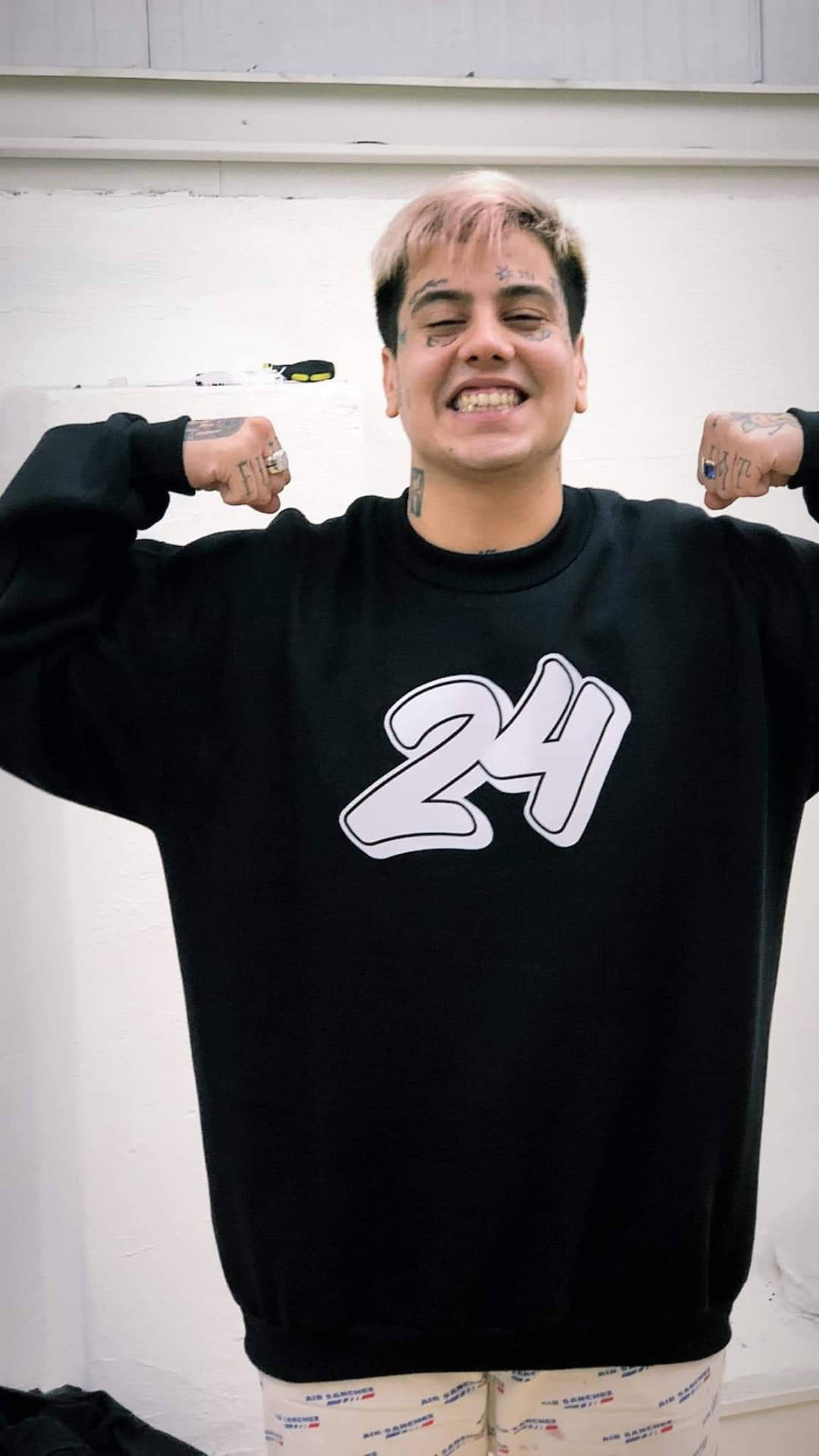 紋身男子穿著印有白色24號的黑色運動衫彎曲手臂。