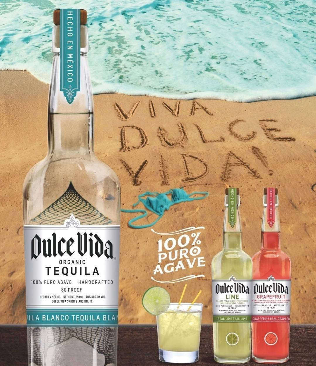 沙灘上的龍舌蘭酒瓶和雞尾酒，伴隨著海浪和沙子上寫的「Viva Dulce Vida」。