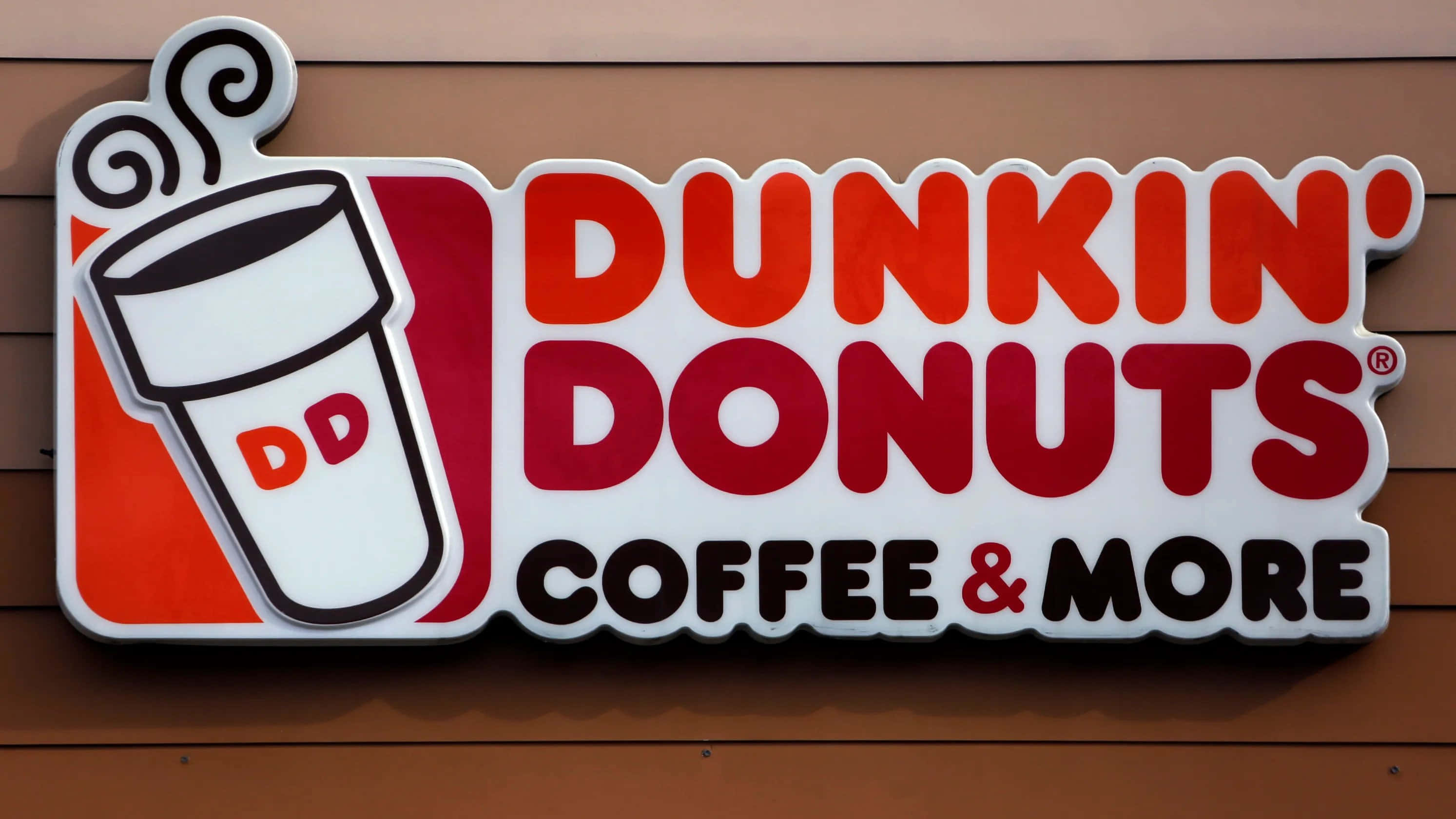 享受Dunkin' Donuts的美味甜甜圈與咖啡 壁紙 — 一個鮮紅色和白色的Dunkin' Donuts標誌，帶有咖啡杯標誌，安裝在棕色木牆上。