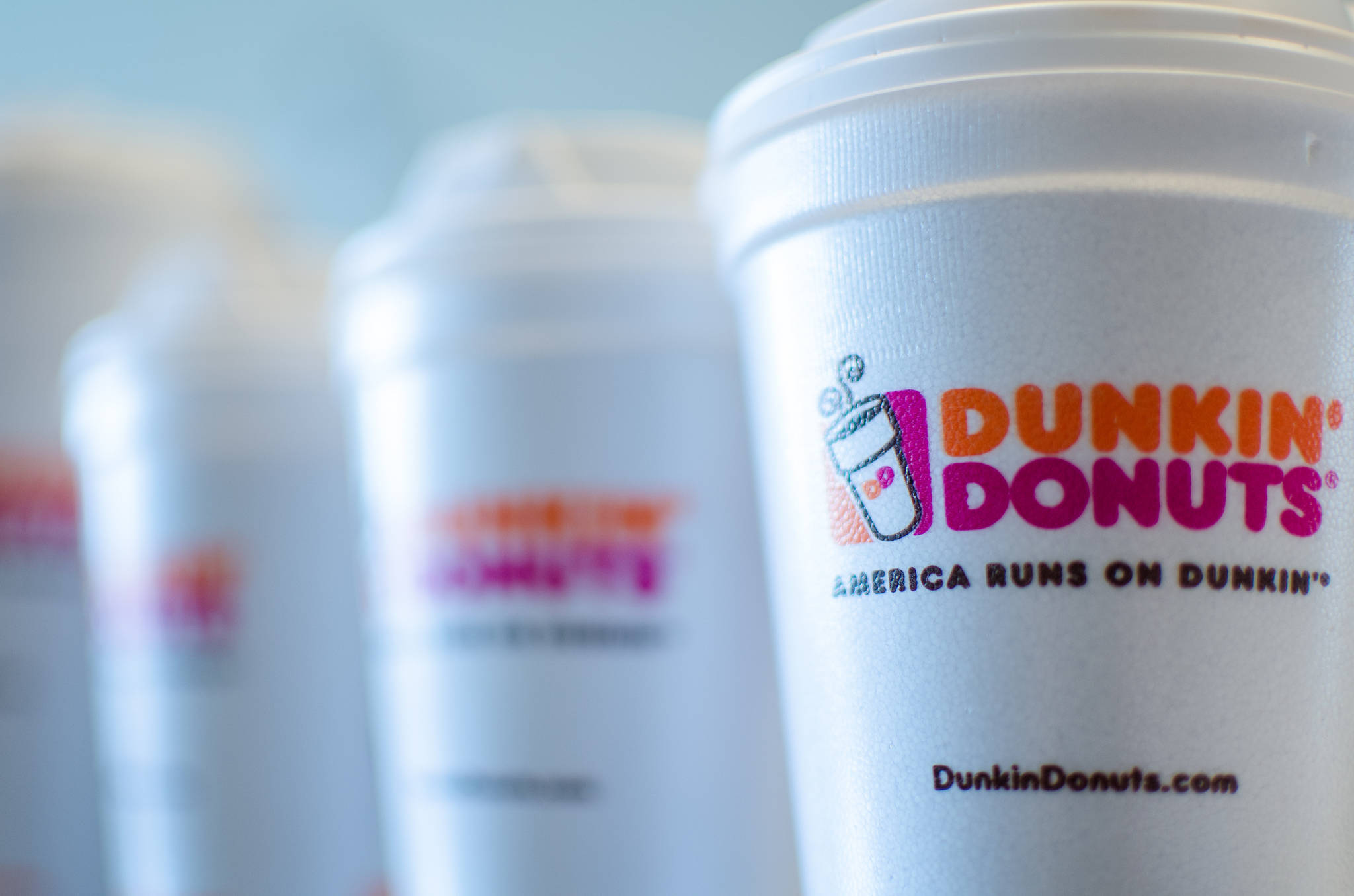 Dunkin' Donuts 白色杯 壁紙 — 淺景深特寫，一排Dunkin' Donuts品牌咖啡杯，最近的杯子清晰對焦。