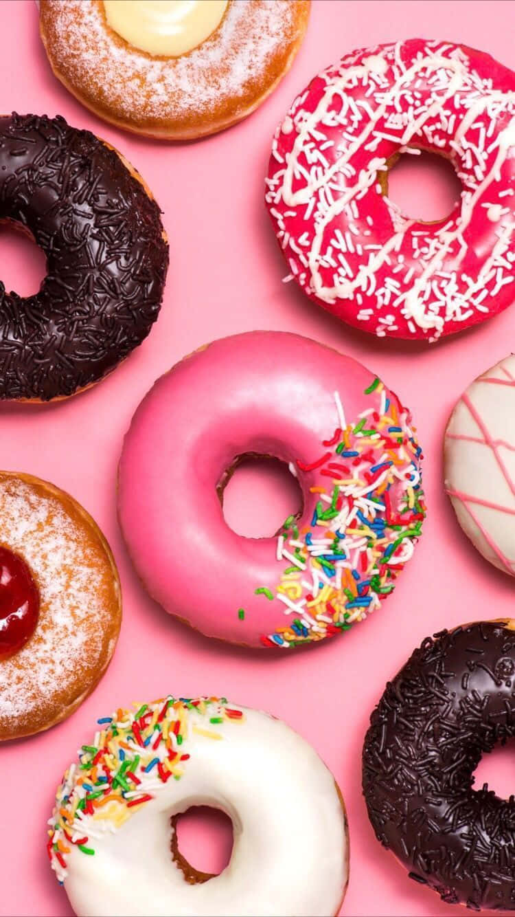 Dunkin' Donuts的咖啡時光 壁紙 — 充滿活力的粉紅色背景展示了各種帶有彩色糖霜、糖粒和朱古力醬的冬甩。