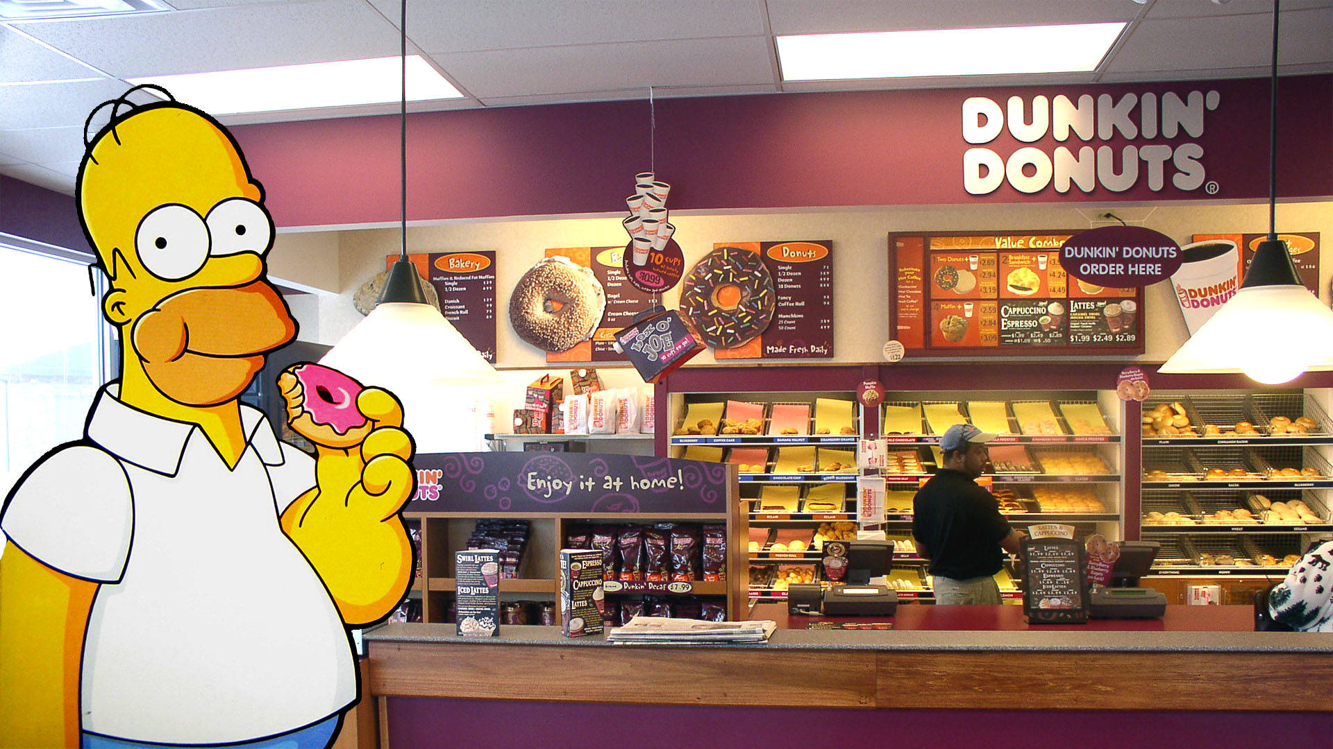Dunkin' Donuts 與荷馬·辛普森 壁紙 — 荷馬·辛普森卡通角色在真實的Dunkin' Donuts烘焙櫃檯前拿著一個粉紅色糖霜甜甜圈。
