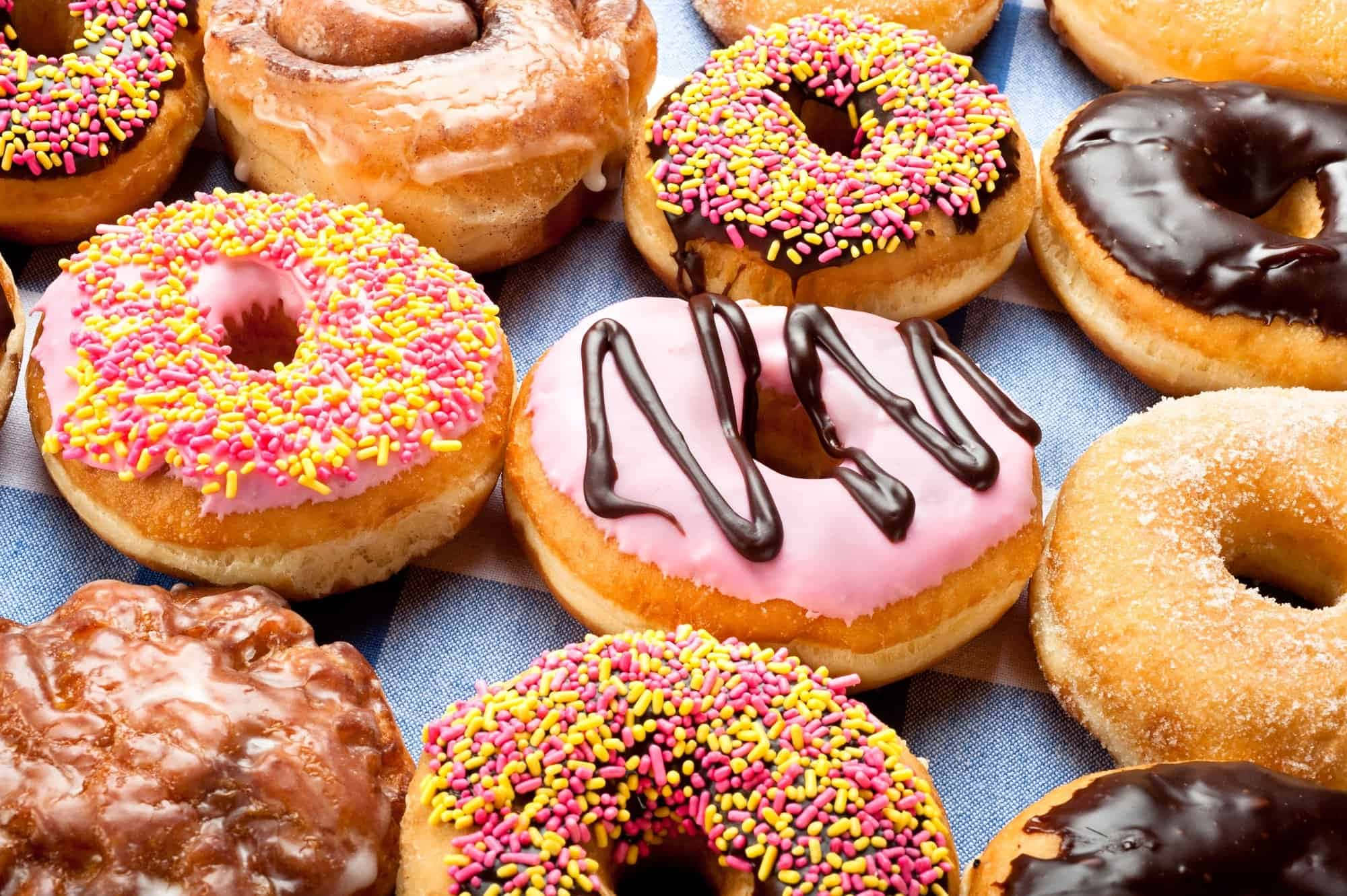 Dunkin' Donuts 頂級天然食材 壁紙 — 色彩繽紛的糖霜和彩針甜甜圈排列在藍色格紋布上。