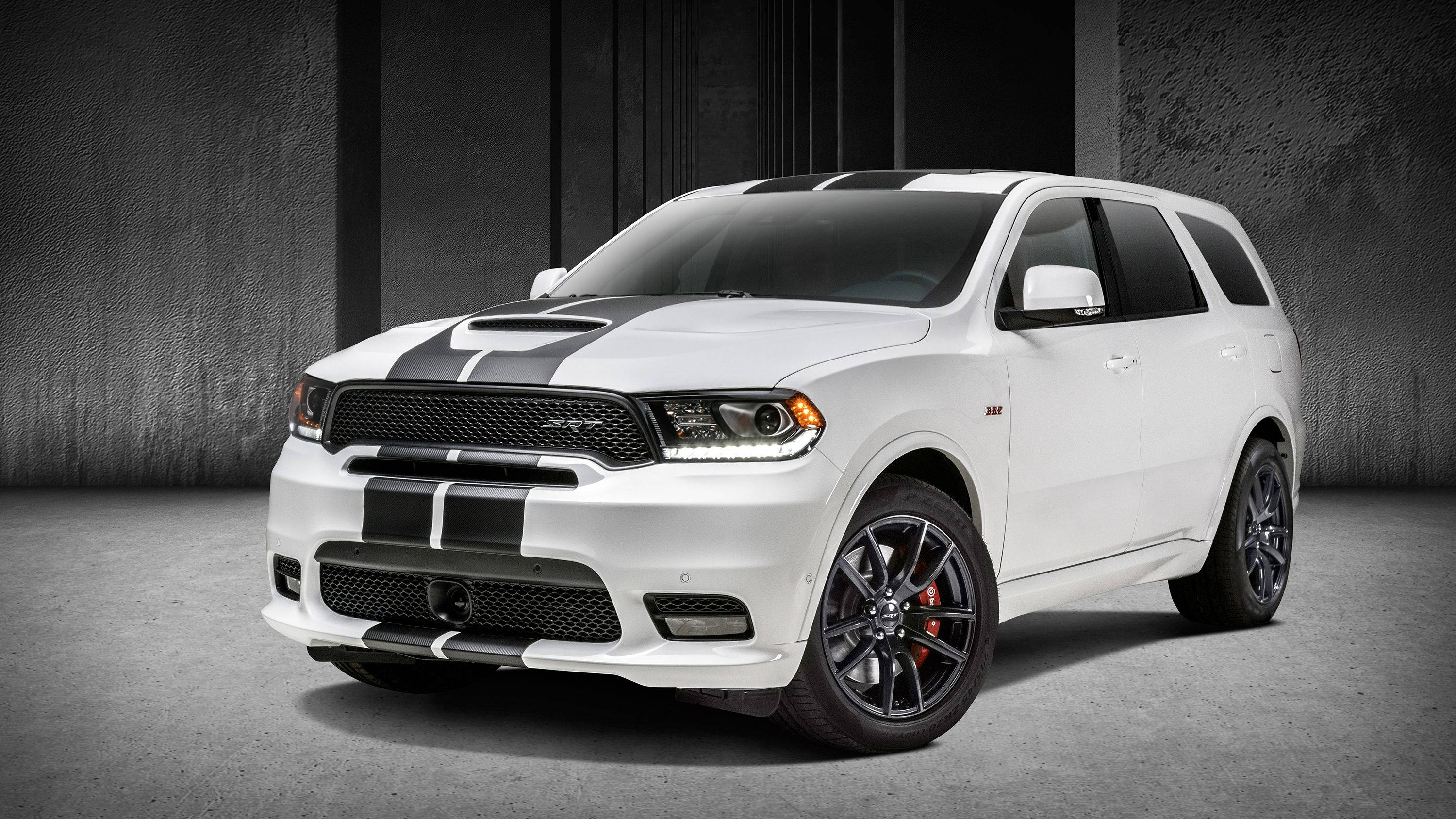 Durango車款工作室照 壁紙 — 一輛白色Dodge Durango SRT，帶有黑色賽車條紋和紅色制動卡鉗，矗立在簡約的混凝土工作室中。