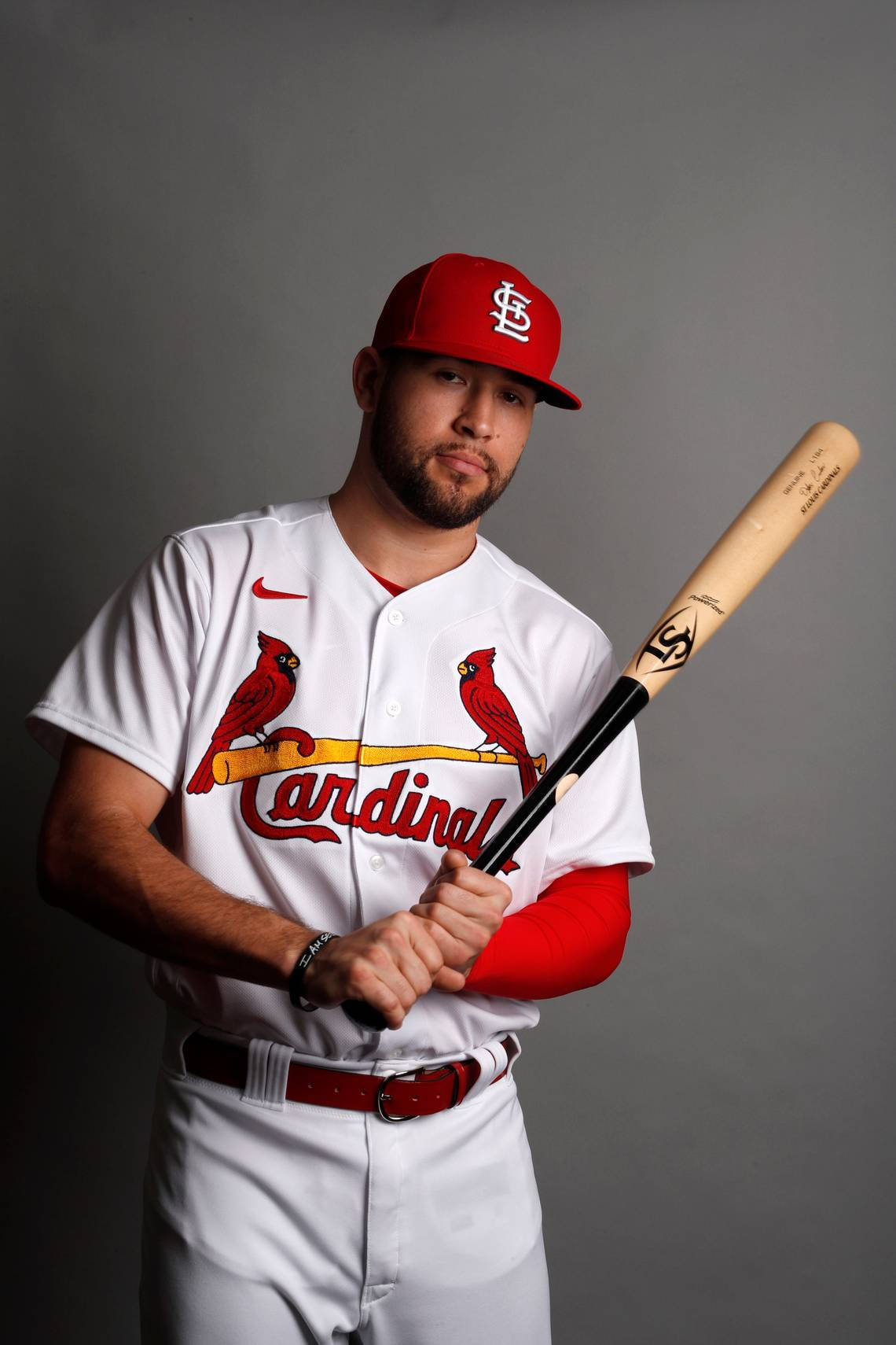 Dylan Carlson - St. Louis Cardinals 的新星球員 壁紙 — 一名身穿聖路易紅雀隊球衣的棒球運動員在純灰色攝影棚背景前手持球棒。