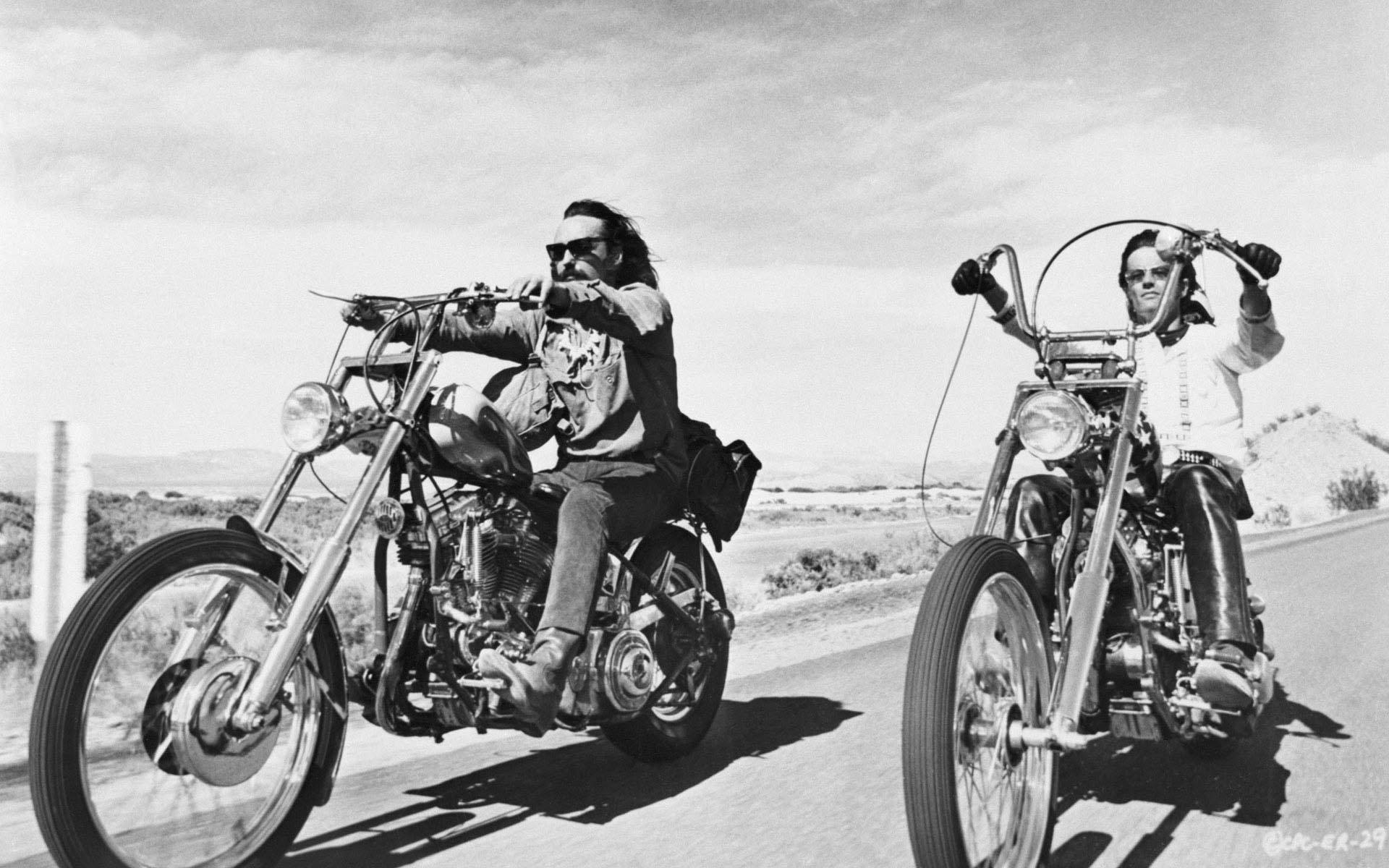 《Easy Rider》經典黑白駕駛畫面 壁紙 — 兩名男子在廣闊天空下，騎著訂製的chopper電單車行駛在陽光明媚的沙漠公路上。