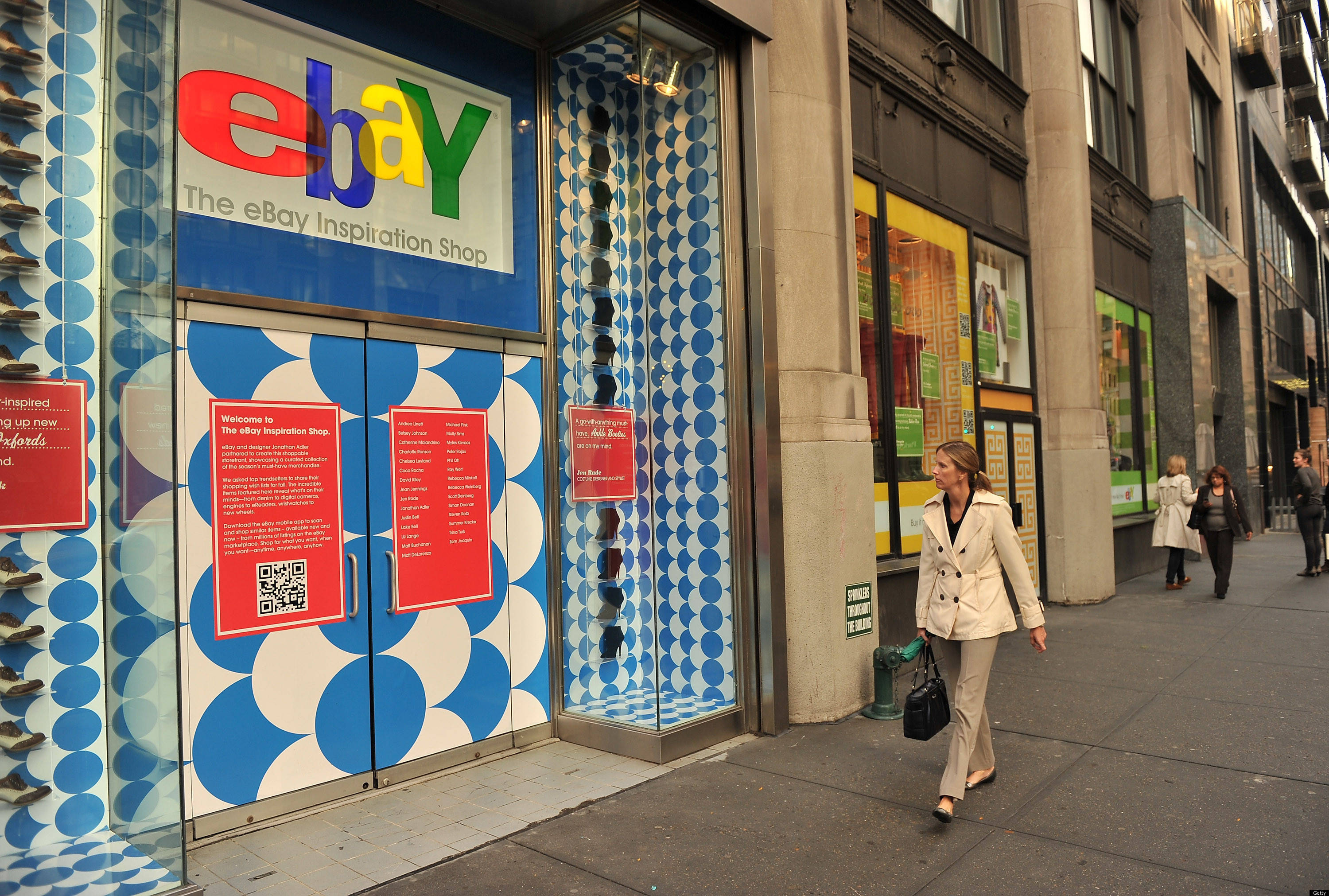 eBay色彩繽紛實體店面 壁紙 — 一位女士走過城市人行道上色彩鮮豔的藍白圖案 eBay Inspiration Shop 店面。