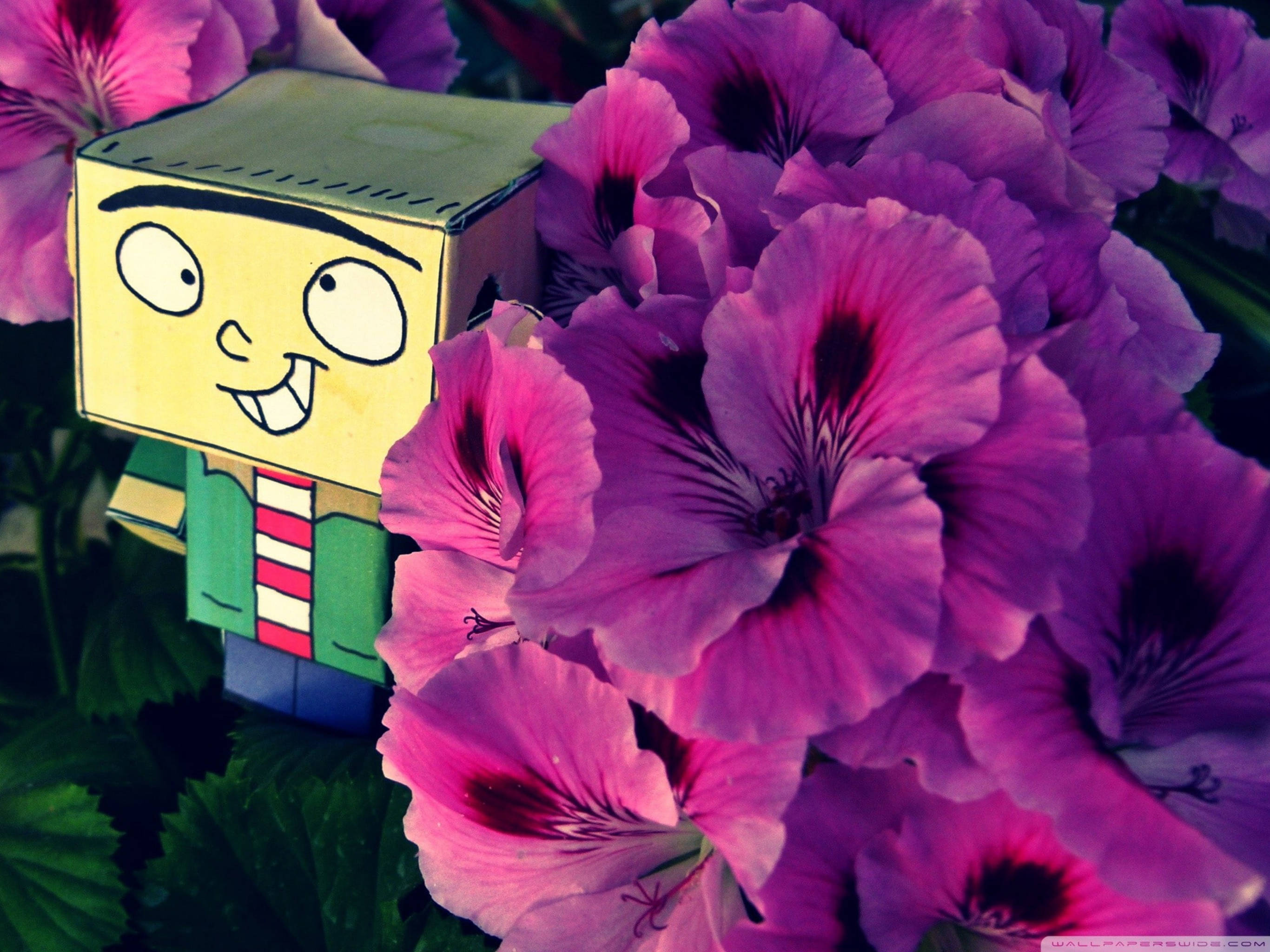 《Ed, Edd n Eddy》可愛愛德Minecraft風格 壁紙 — 一個穿著條紋襯衫、快樂的黃色紙玩具公仔在充滿活力的紫色和粉紅色天竺葵花中微笑。