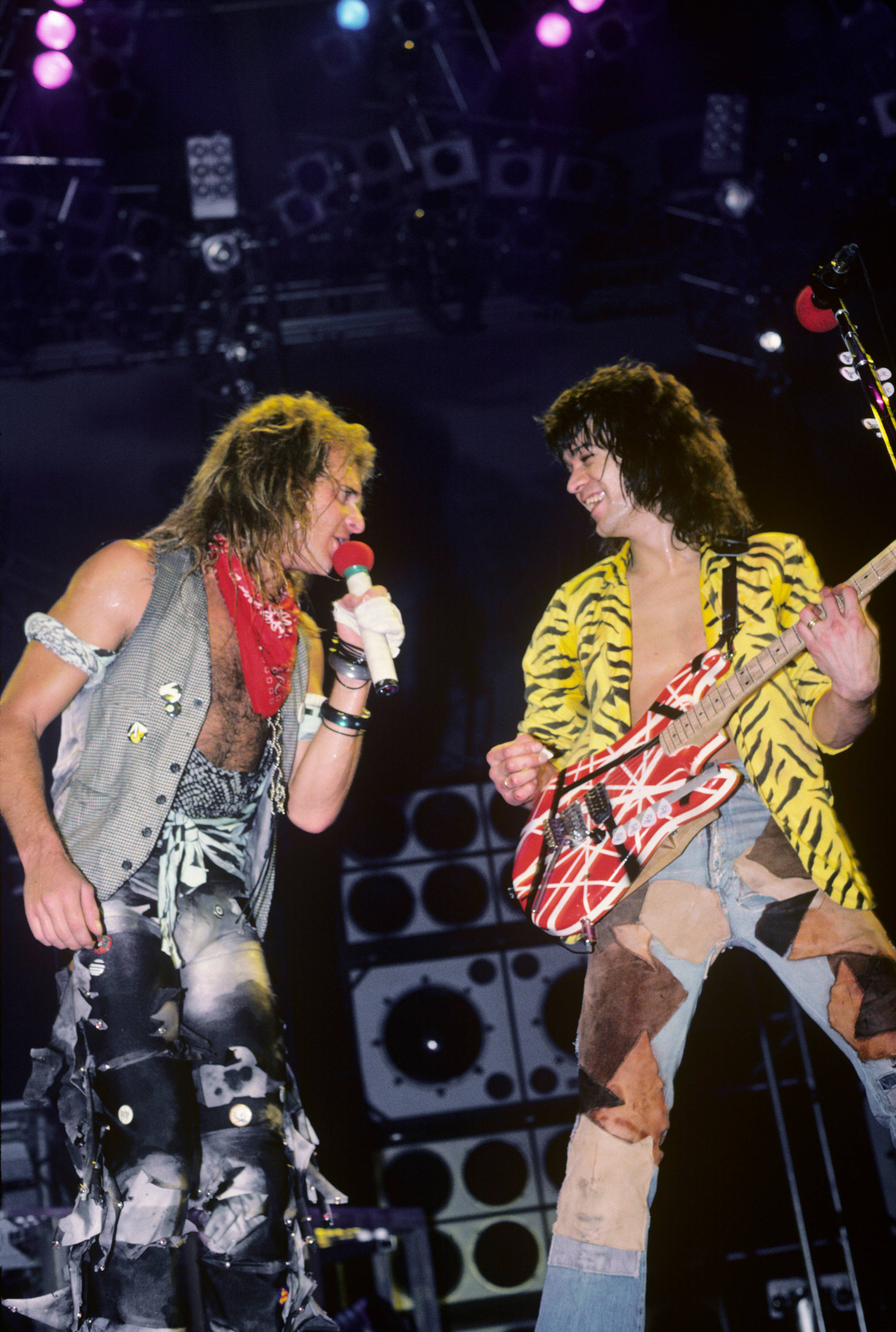 Eddie Van Halen 與 David Lee Roth 壁紙 — 兩位搖滾音樂家在色彩繽紛的聚光燈下，拿著結他和咪高峰在舞台上充滿活力地表演。