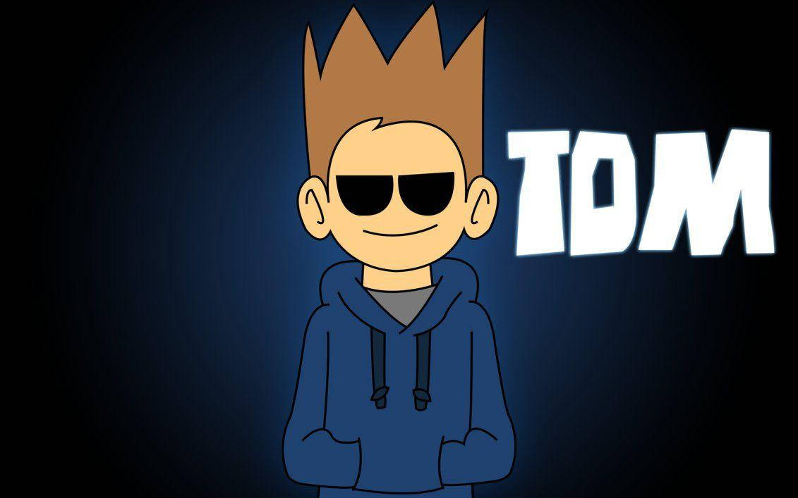 Eddsworld 的 Tom 戴著酷炫太陽眼鏡 壁紙 — 一個卡通角色，擁有尖刺的棕色頭髮和太陽眼鏡，穿著藍色連帽衫，背景是深藍色漸變，名字TOM以發光的白色字母呈現。