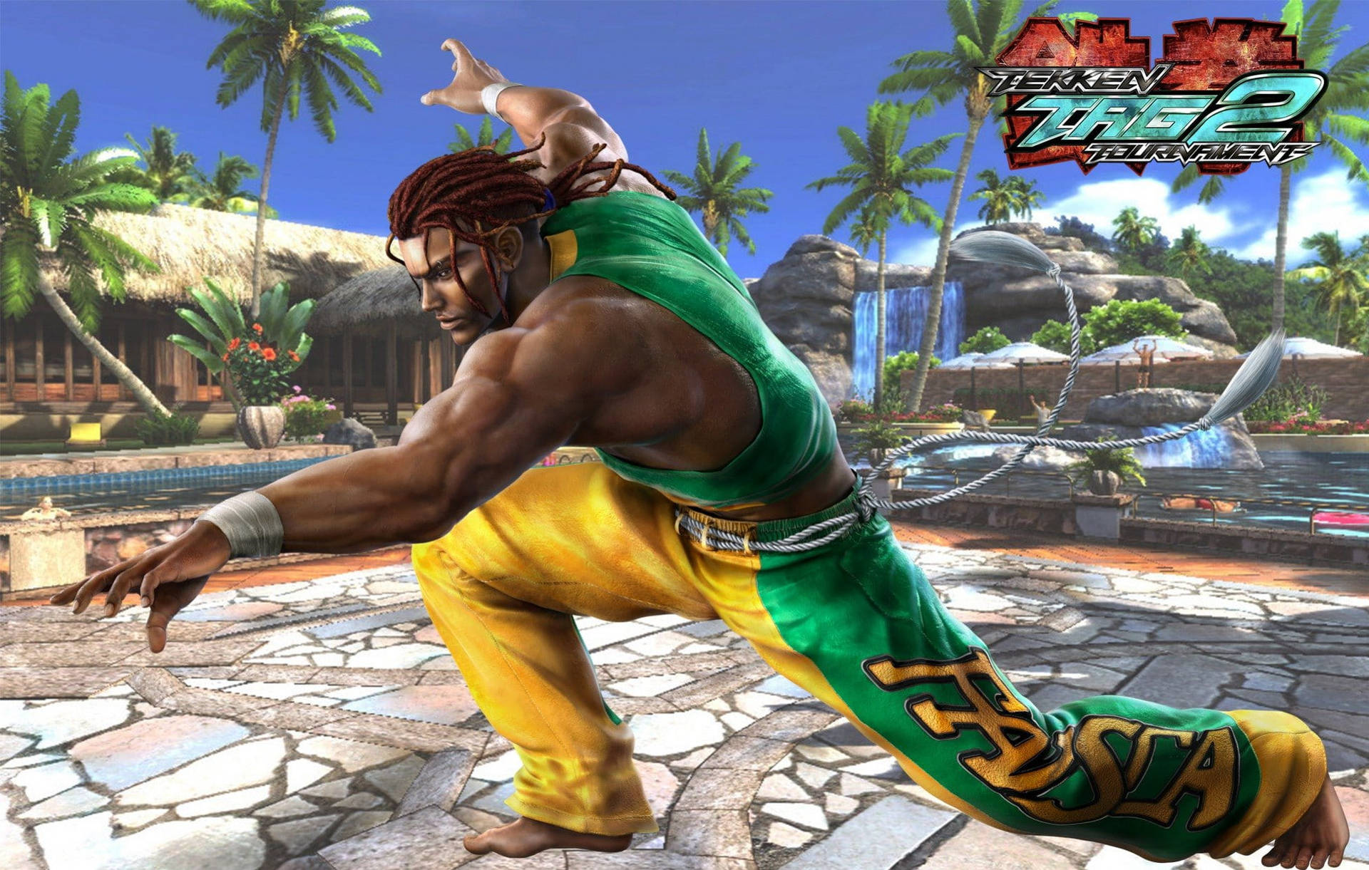 Eddy Gordo - Tekken 遊戲中的卡波耶拉戰士 壁紙 — 一名肌肉發達的戰士身穿綠色和黃色道服，在熱帶石庭院中執行動態武術動作，背景有棕櫚樹和瀑布。