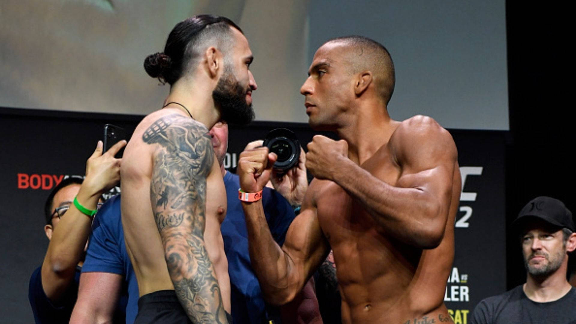 兩位赤裸上身的MMA拳手在稱重活動中緊張地互相凝視。