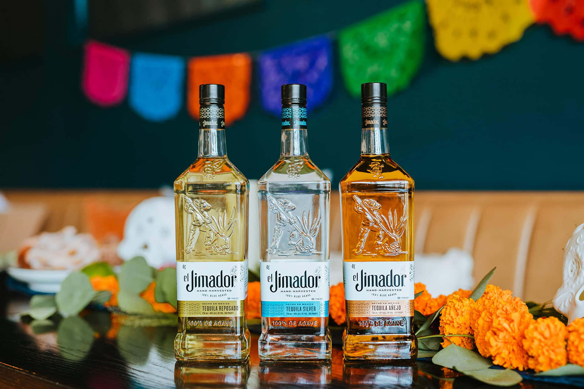 三支 El Jimador 龍舌蘭酒瓶，配有萬壽菊和 papel picado 裝飾。
