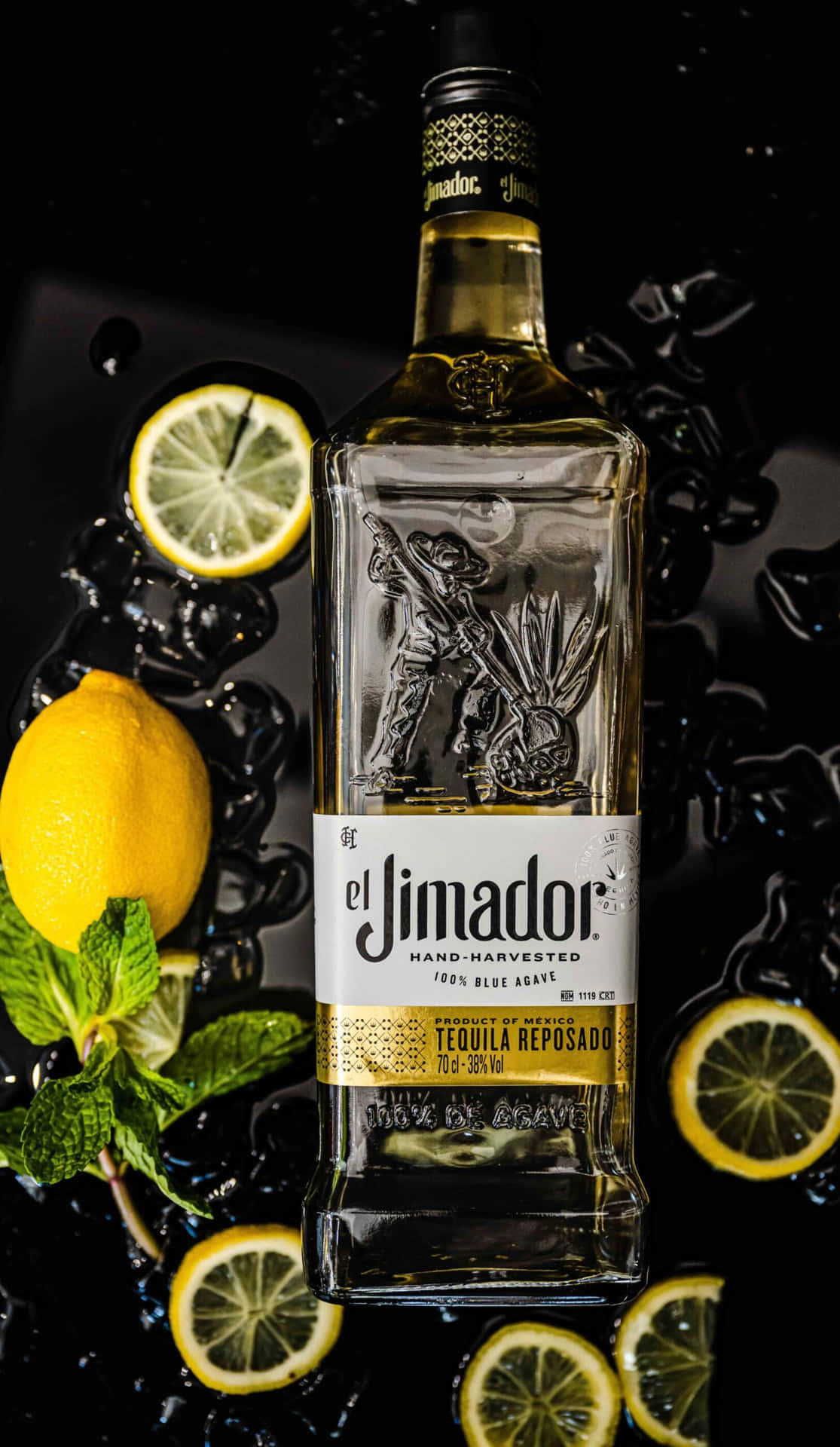 一瓶 El Jimador 龍舌蘭酒在黑暗潮濕的表面上被檸檬和薄荷環繞。