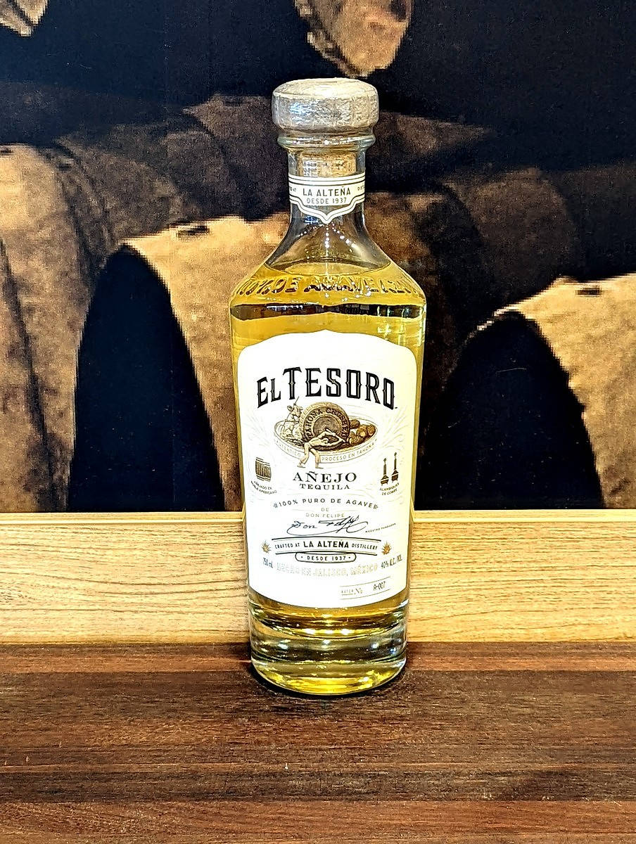一瓶 El Tesoro Añejo 龍舌蘭酒在木質表面上。