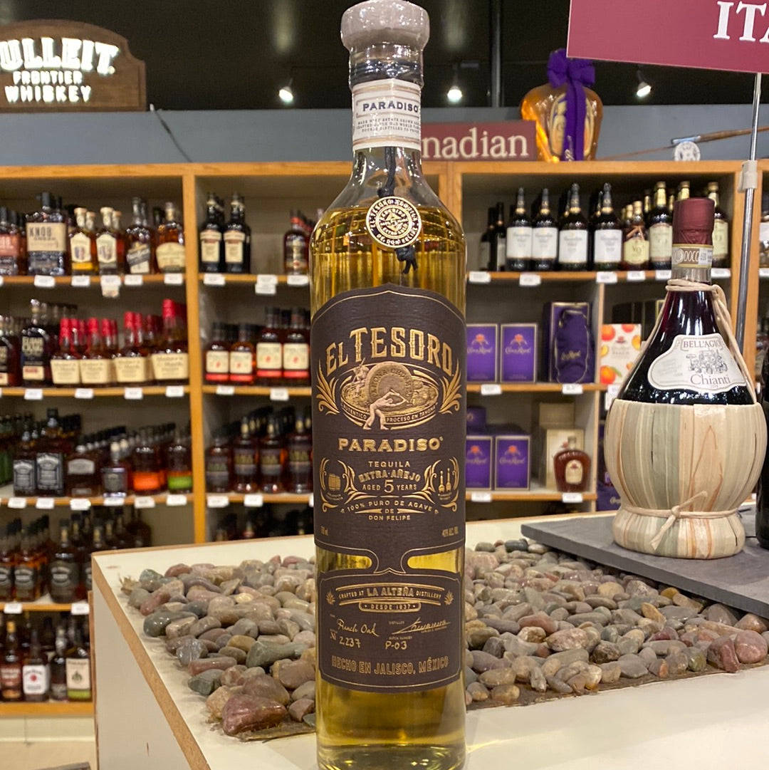 一瓶 El Tesoro Paradiso 龍舌蘭酒放在酒類商店的鵝卵石展示架上。