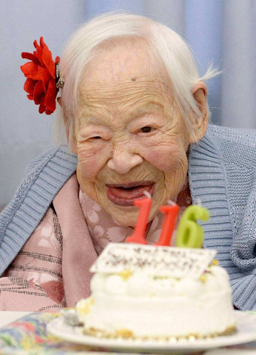一位老婦人微笑著吹熄116歲生日蛋糕上的蠟燭。