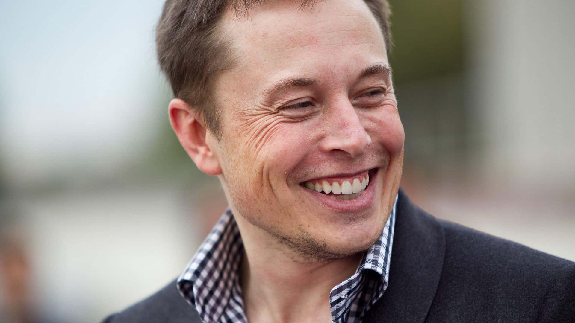 Elon Musk 笑到眼都瞇埋，好開心咁笑。