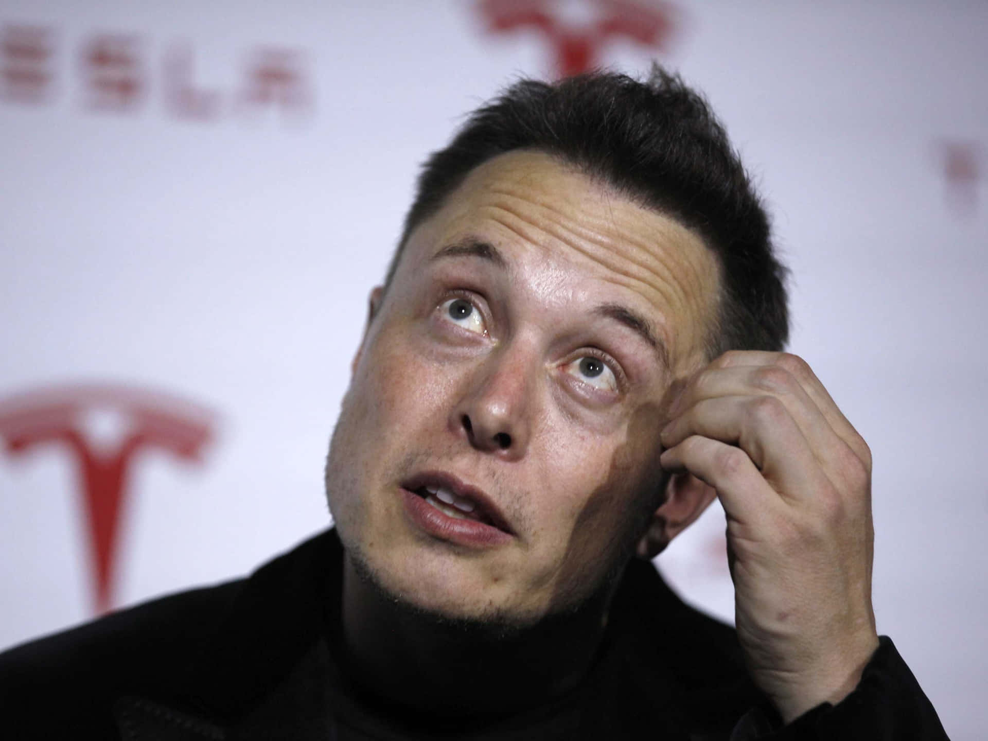 伊隆·馬斯克在特斯拉活動中觸摸耳朵並向上看。