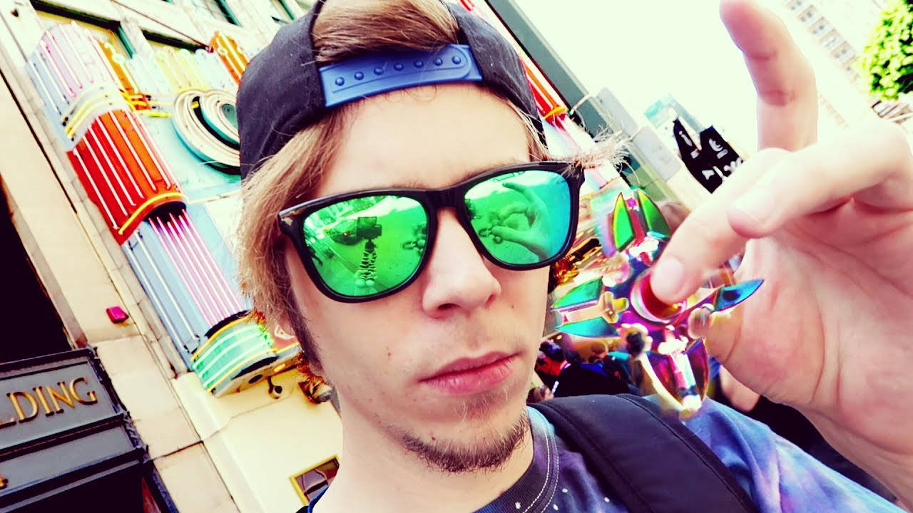 戴著太陽眼鏡和帽子的年輕男子在色彩繽紛的城市街道上自拍。