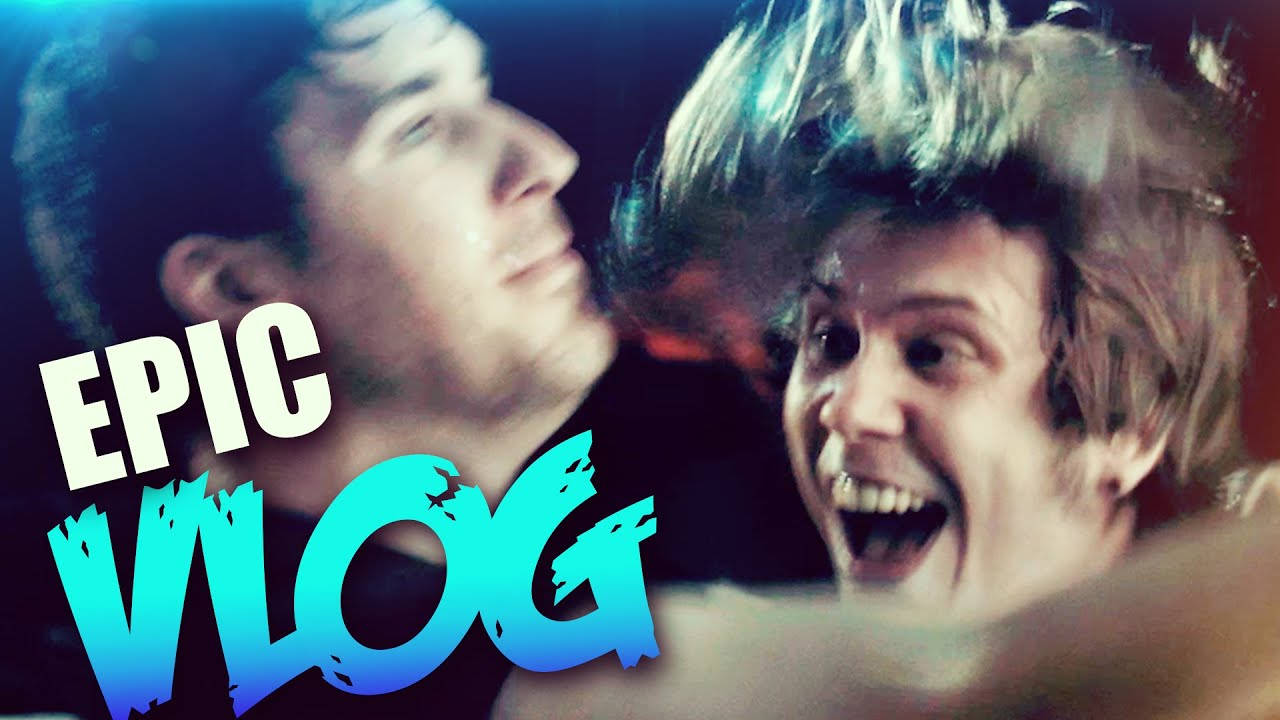 ElrubiusOMG攜巨製Vlog衝向大銀幕！ 壁紙 — 兩個男人在動態特寫中，一個咧嘴大笑，另一個看起來冷靜，帶有粗體藍白「EPIC VLOG」文字疊加。