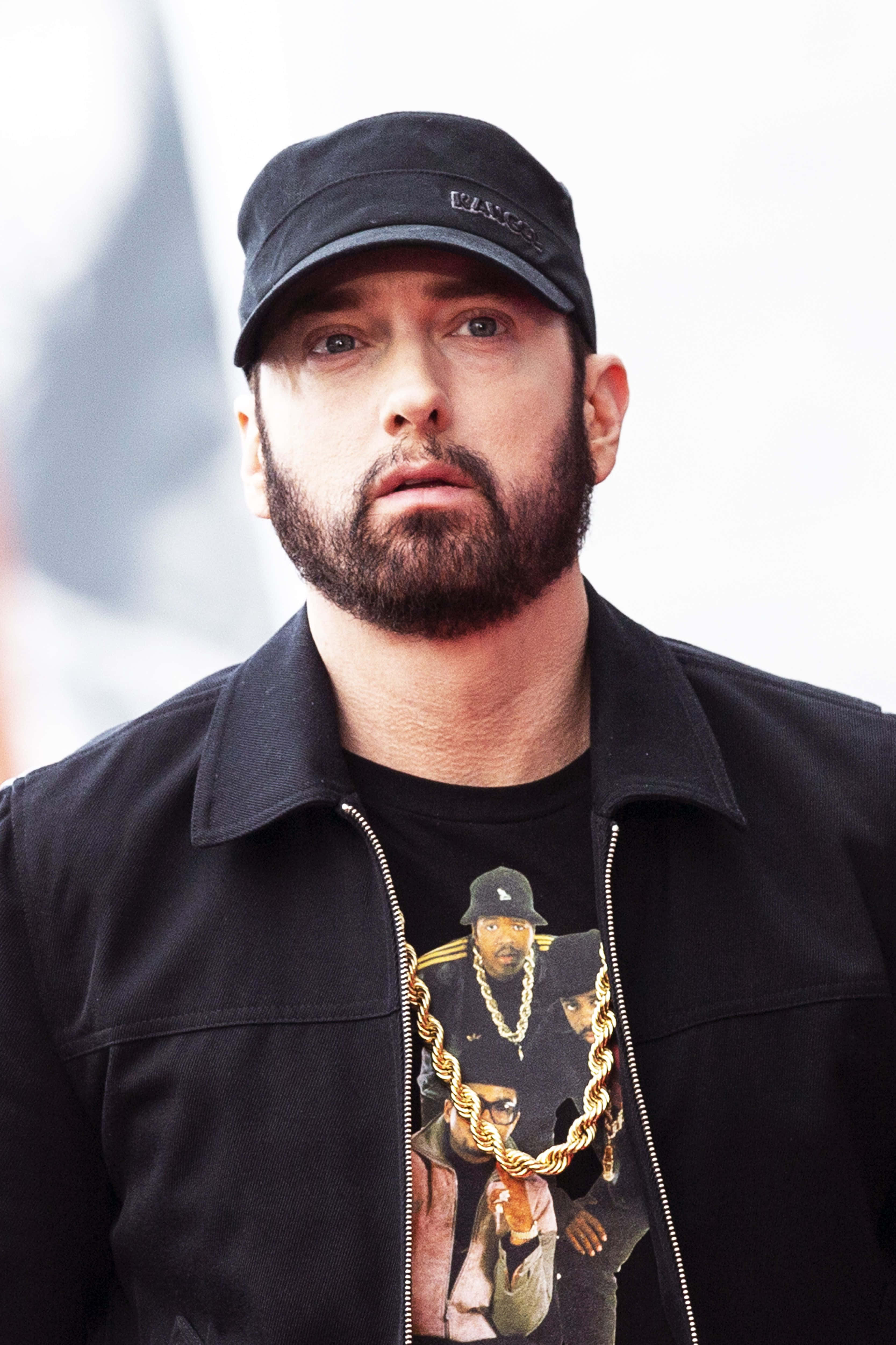 Eminem 桌布 壁紙 — Eminem 嘅特寫肖像，戴住黑色帽同外套，著住有金色鏈設計嘅圖案T恤。